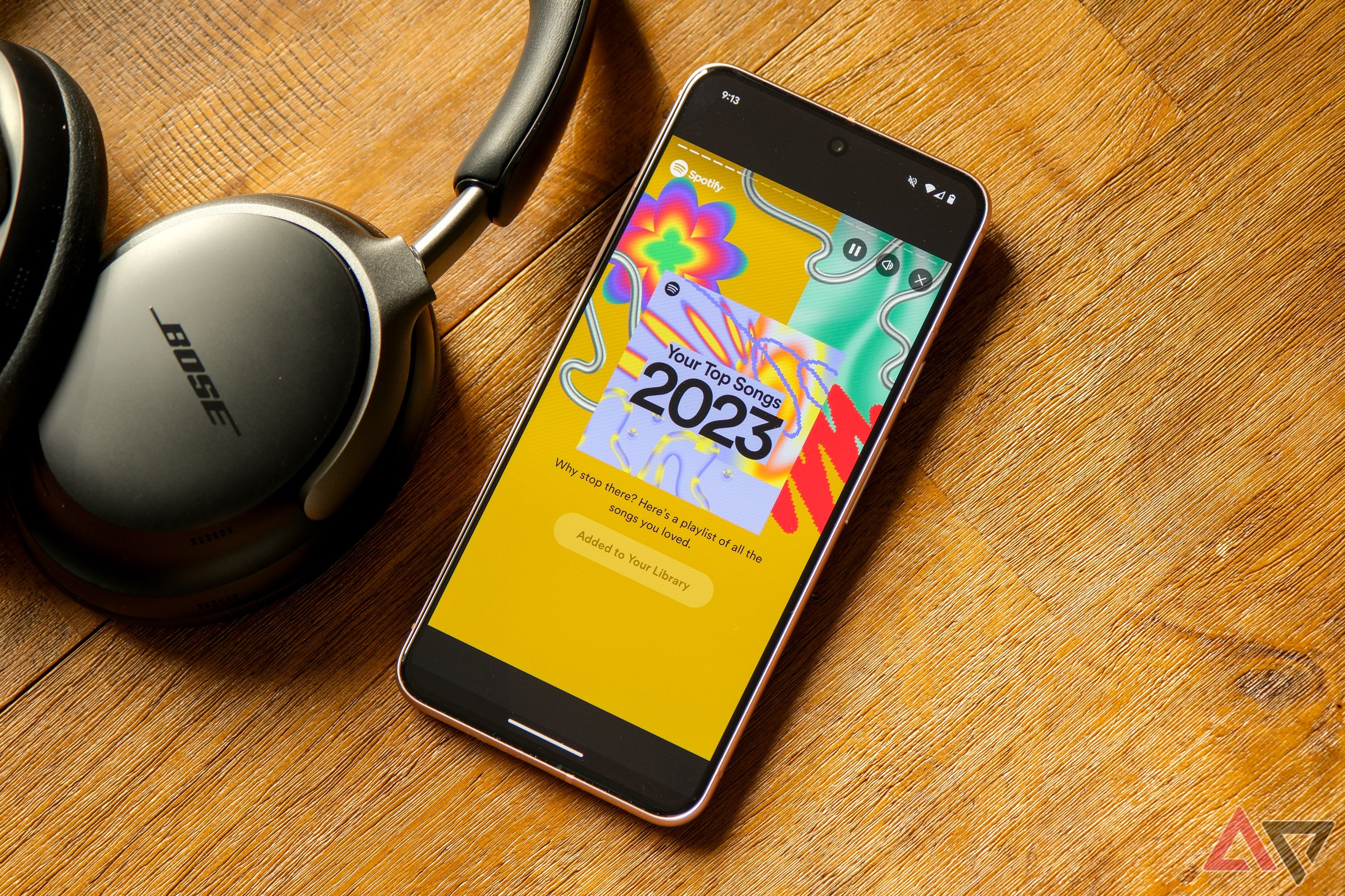 A smartphone displaying the Spotify app next to a pair of Bose headphones