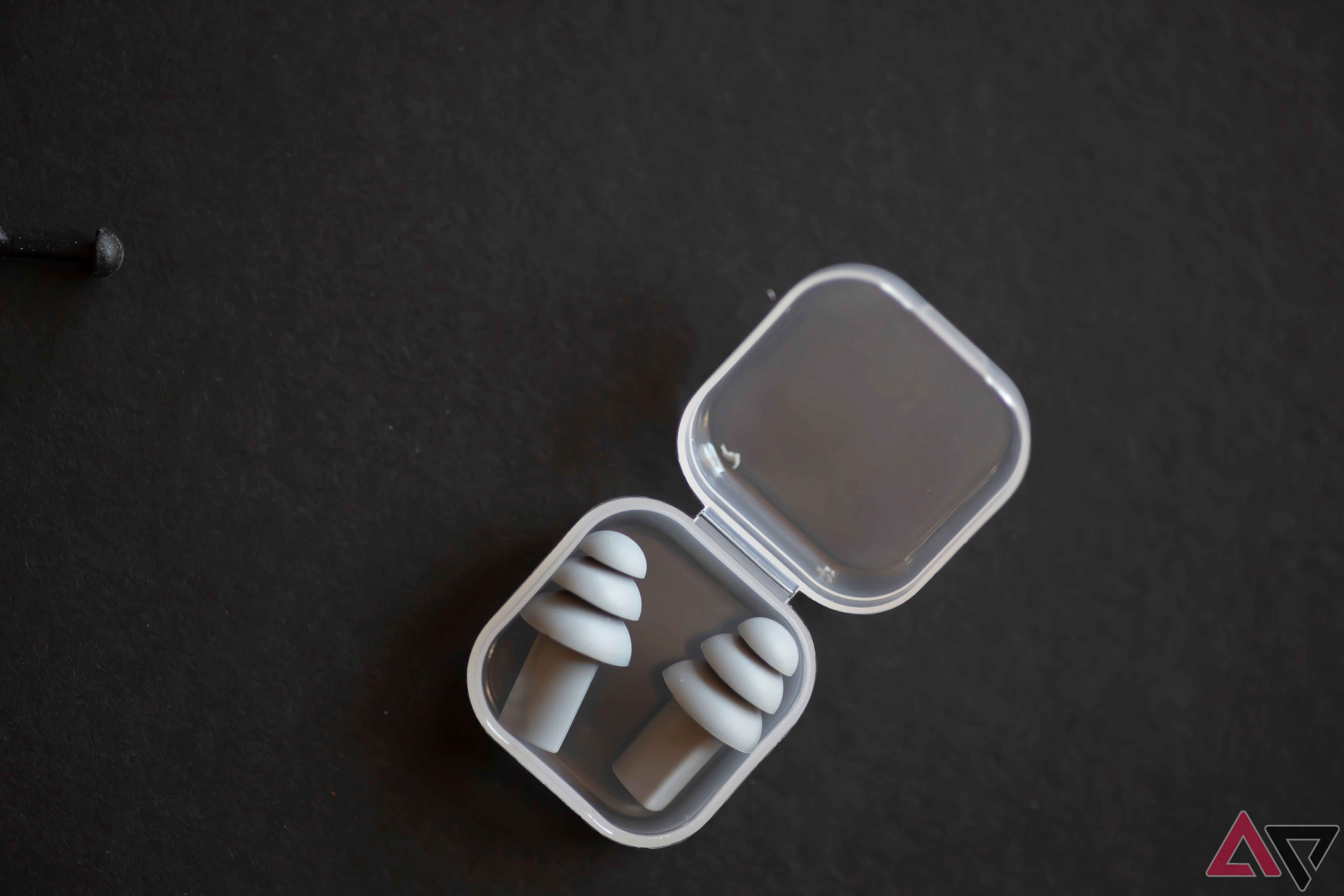 Gray earplugs in plastic case on white background