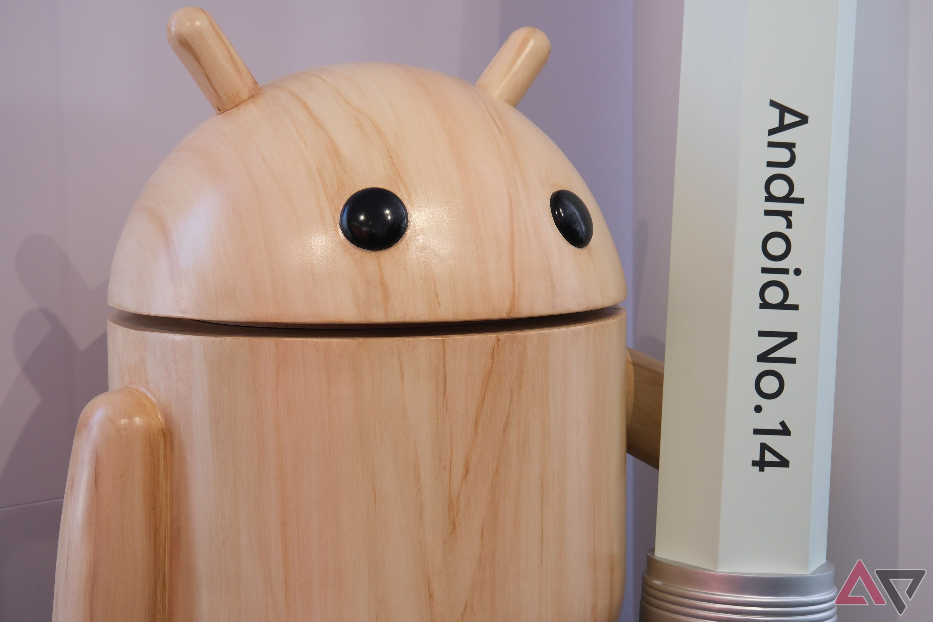 A wooden Android mascot holding a pencil reading 'Android No. 14'