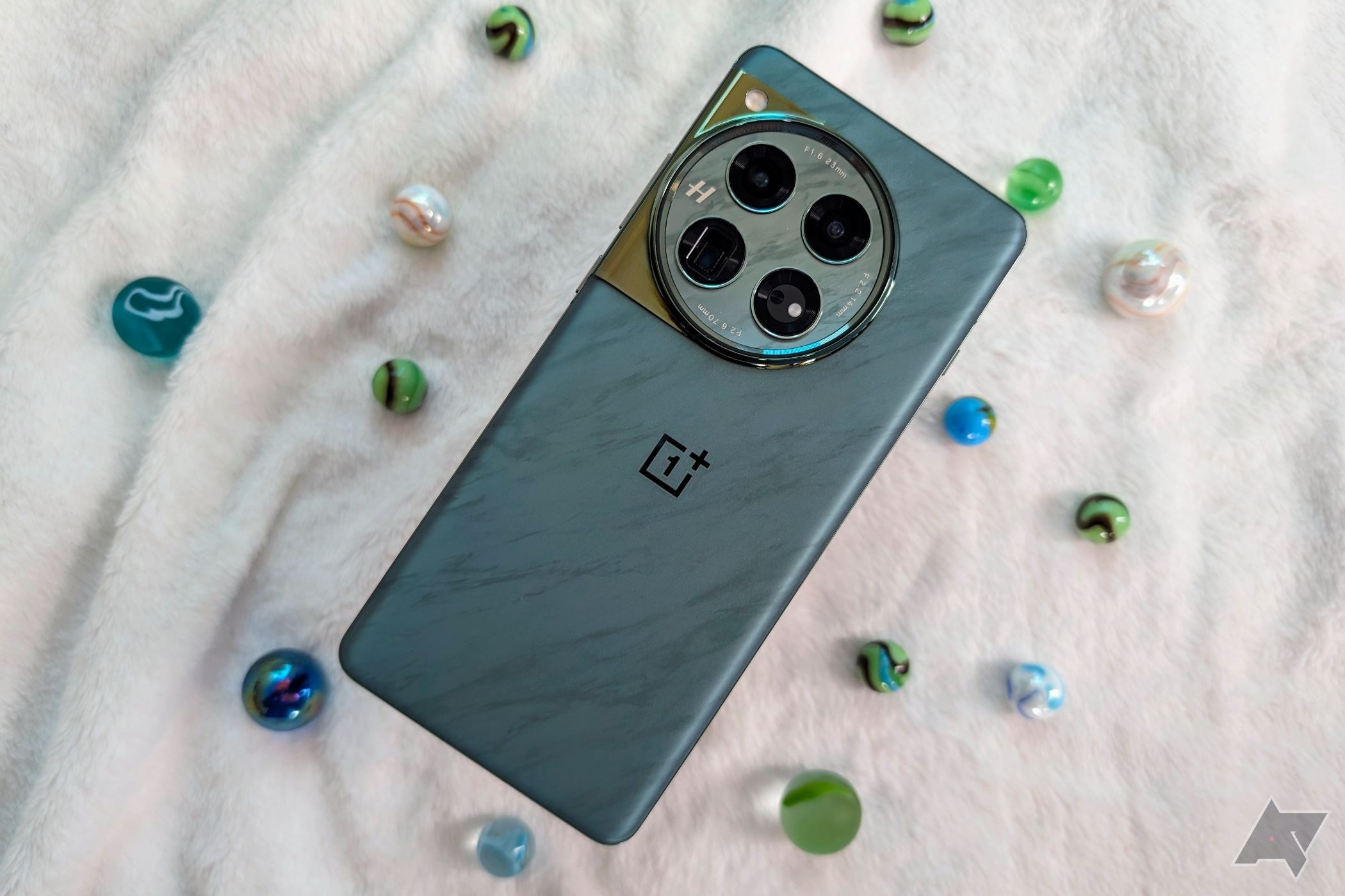 OnePlus 12 on a fuzzy blanket with colored marbles around it