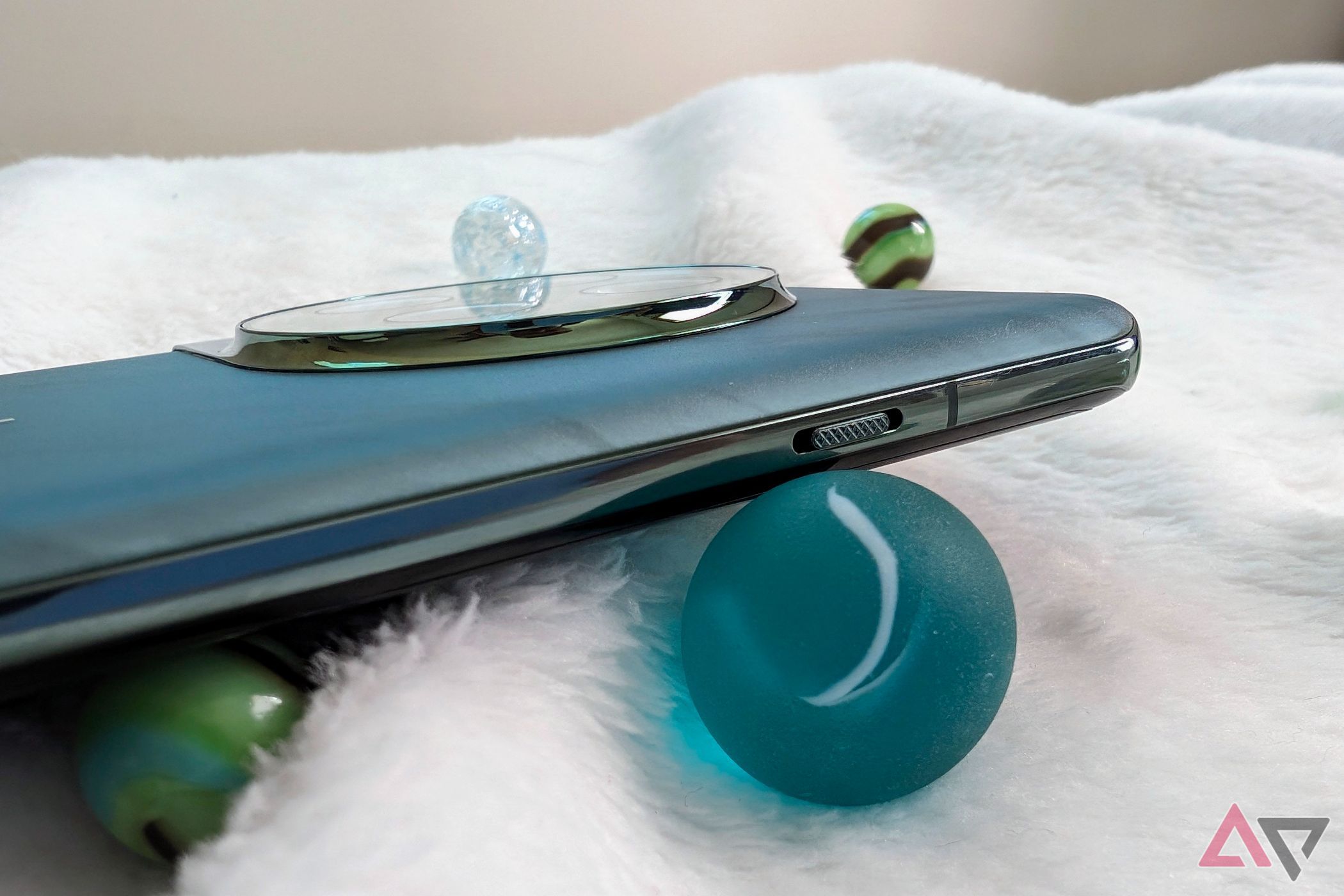 OnePlus 12 alert slider‍ on a fuzzy blanket with colored marbles around it