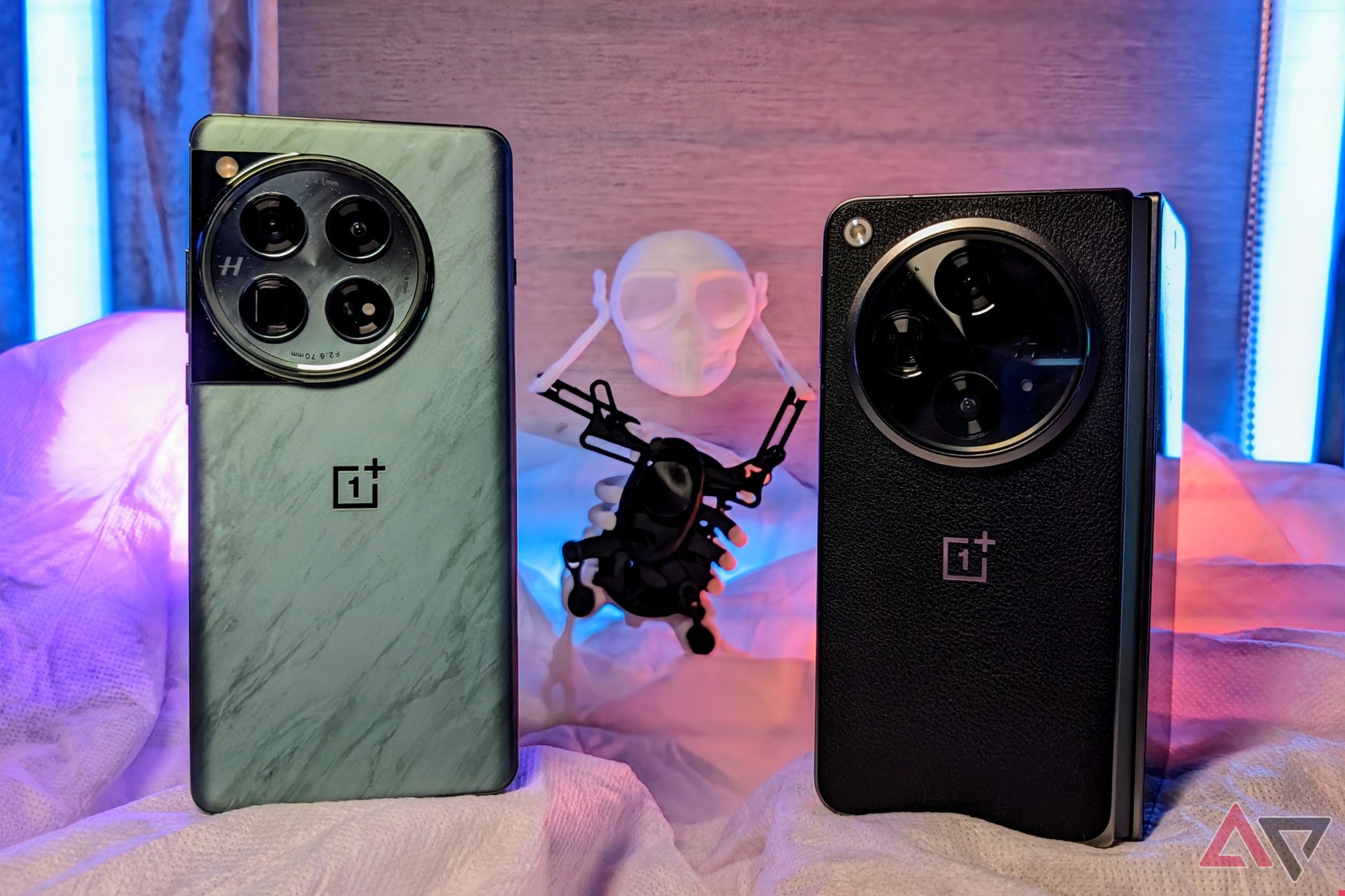 OnePlus 12 and the OnePlus Openon a table with a skeleton behind it with RGB lights