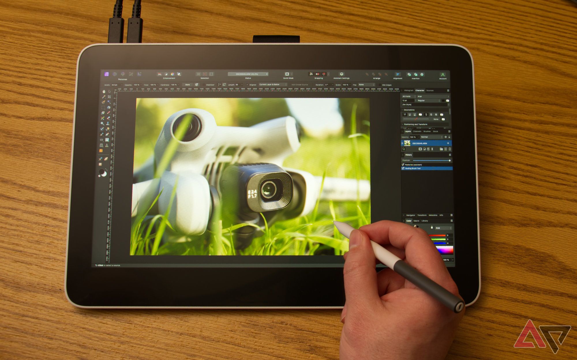 Wacom One 13 Touch lying on a desk with a hand holding a stylus, used for editing an image of a drone camera