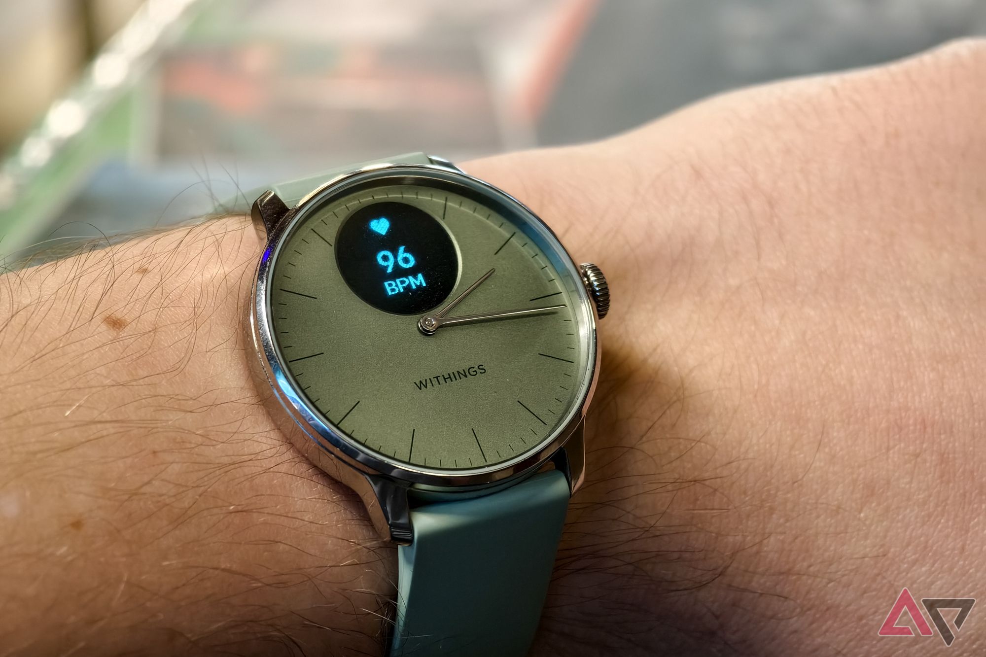 Withings ScanWatch Light in Green, with the display on, photographed on a man's wrist with a close-up on the watch face showing heartrate