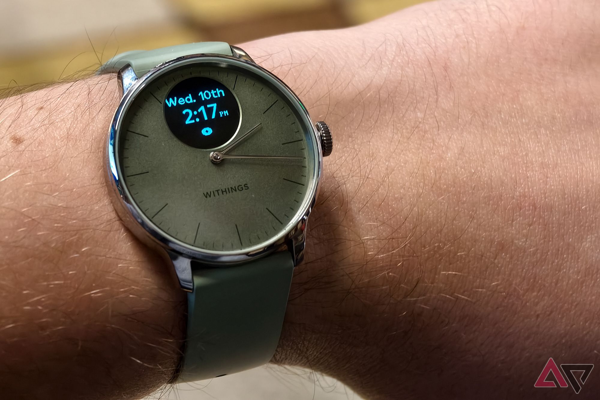 Withings ScanWatch Light in Green, with the display on, photographed on a man's wrist showing the time