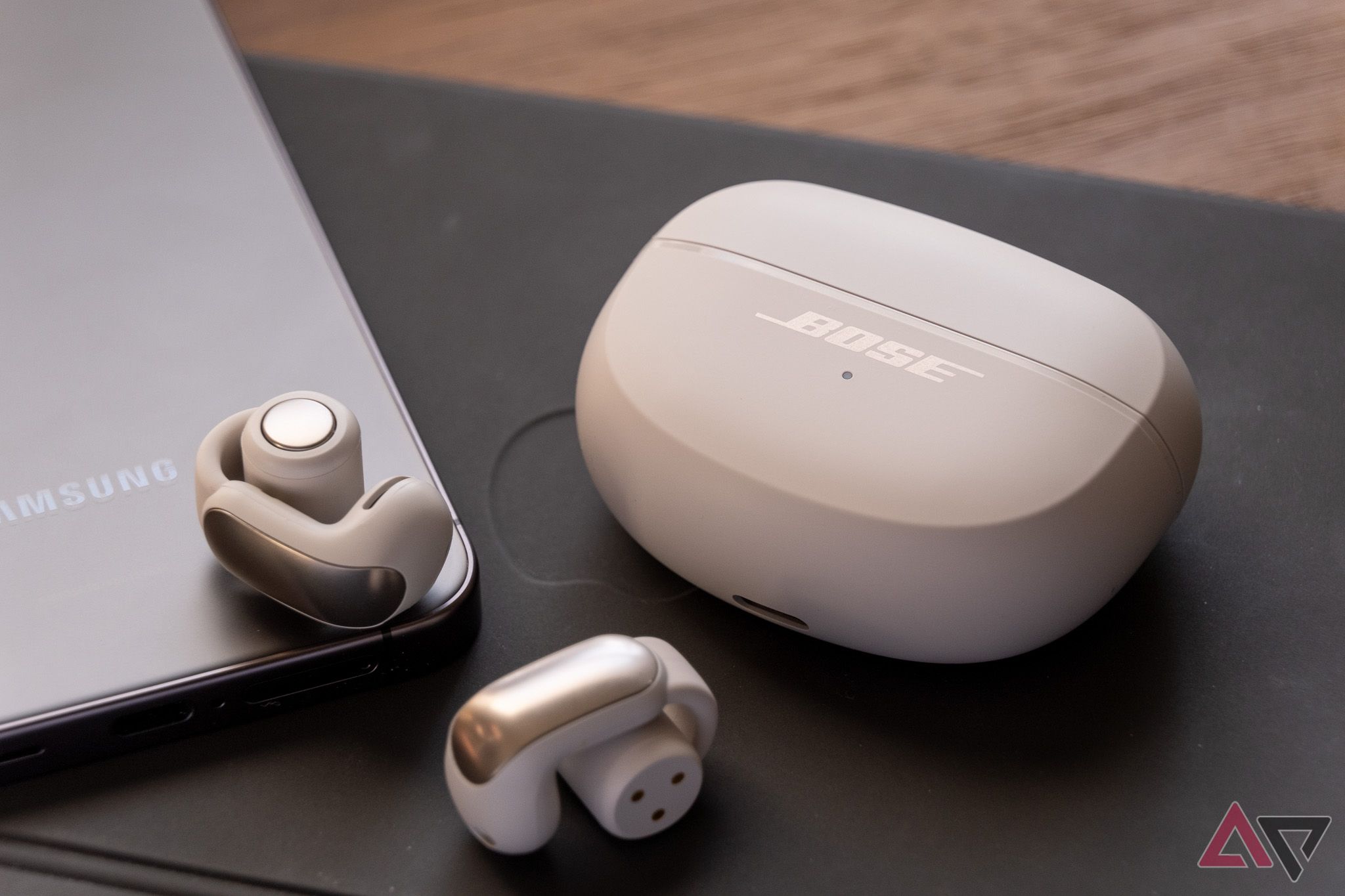 The Bose Ultra Open earbuds next to their case, sitting on top of an iPad