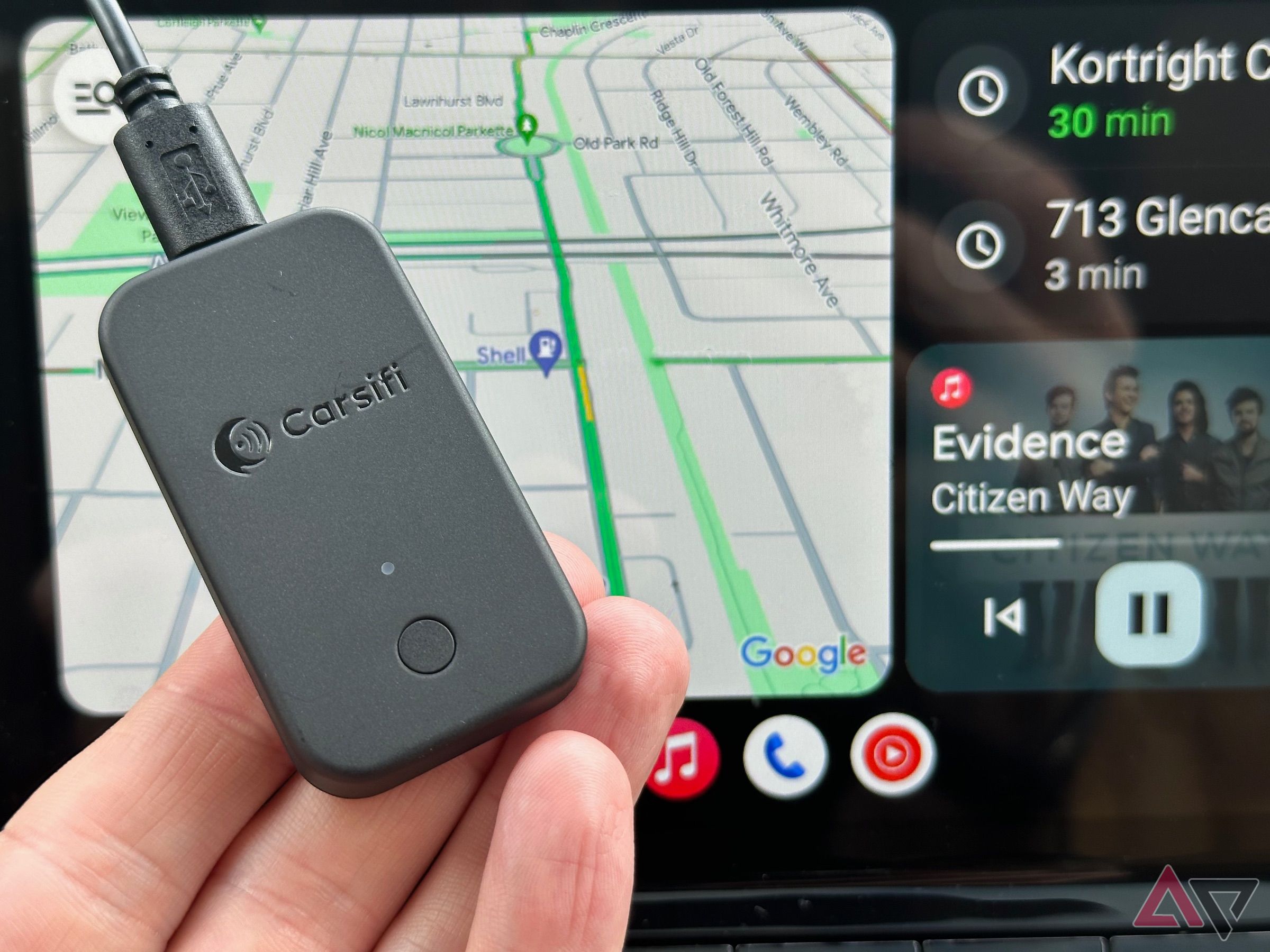 Fingers holding Carsifi Wireless Android Auto Adapter in front of Android Auto screen showing Google Maps and Apple Music.