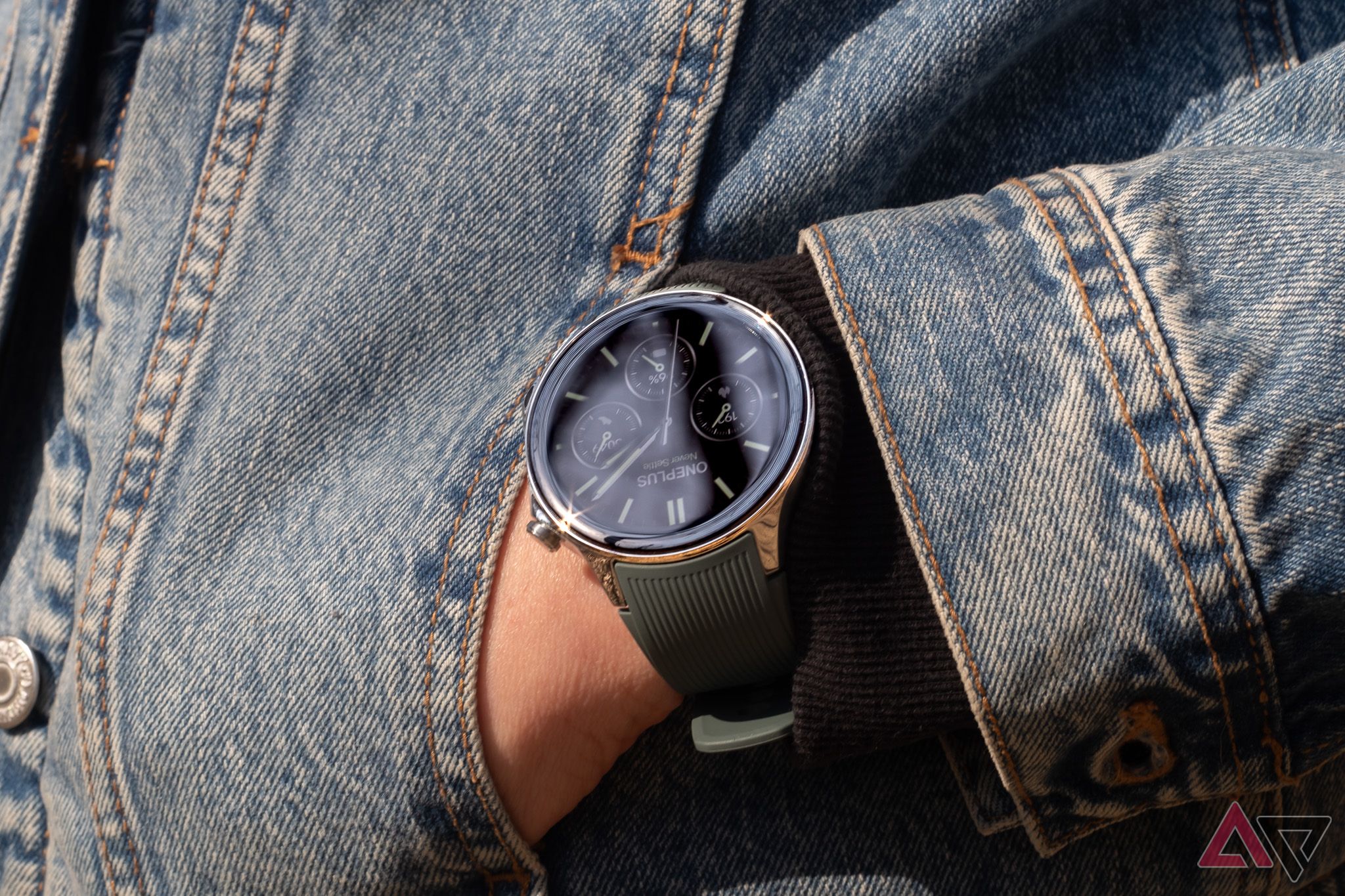 A smartwatch on an arm, with a hand in a pocket of a denim jacket