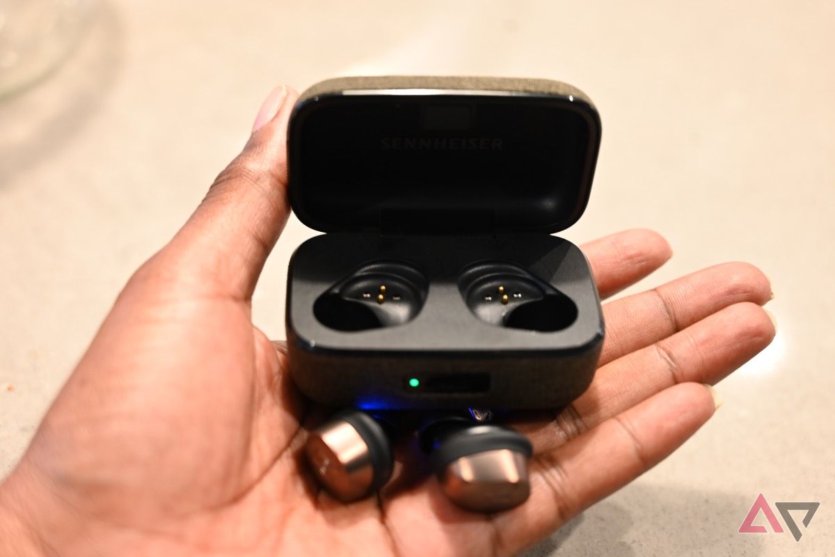 Close up of Sennheiser Momentum True Wireless 4 with charging case held in hand