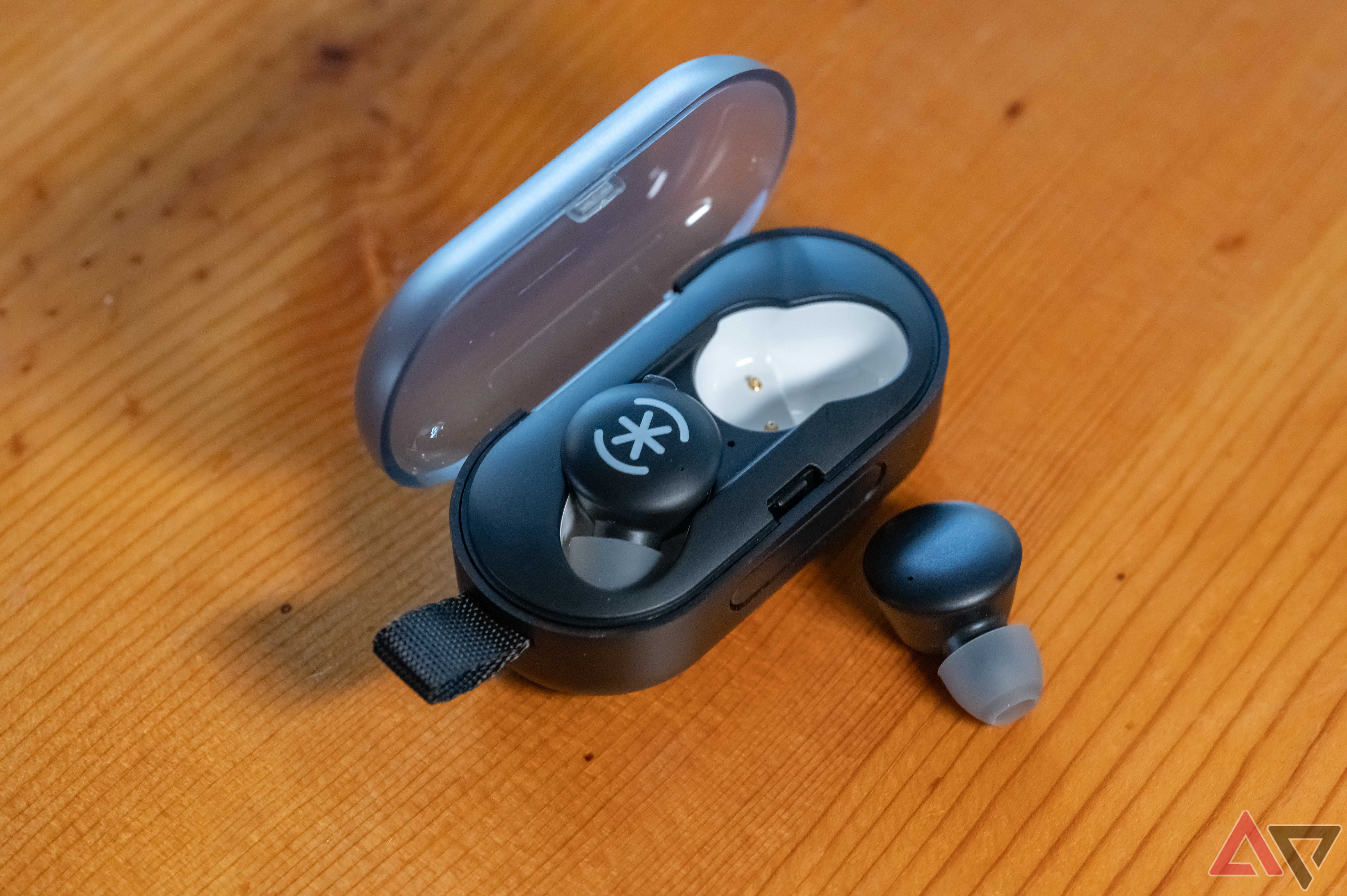 Speck Gemtones Pro with one earbud in charging case and one outside of charging case.