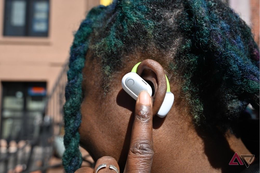 African-American woman wearing white-and-neon-green Baseus Eli Sport 1 Open-Ear TWS Earbuds activatng gesture controls by tapping.