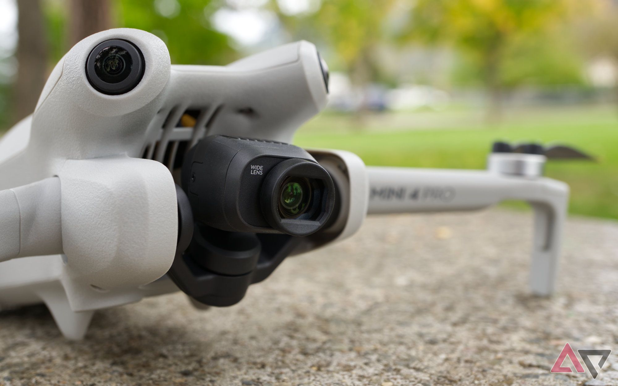 DJI Mini 4 Pro with Wide Angle lens, sitting on concrete with greenery in the background