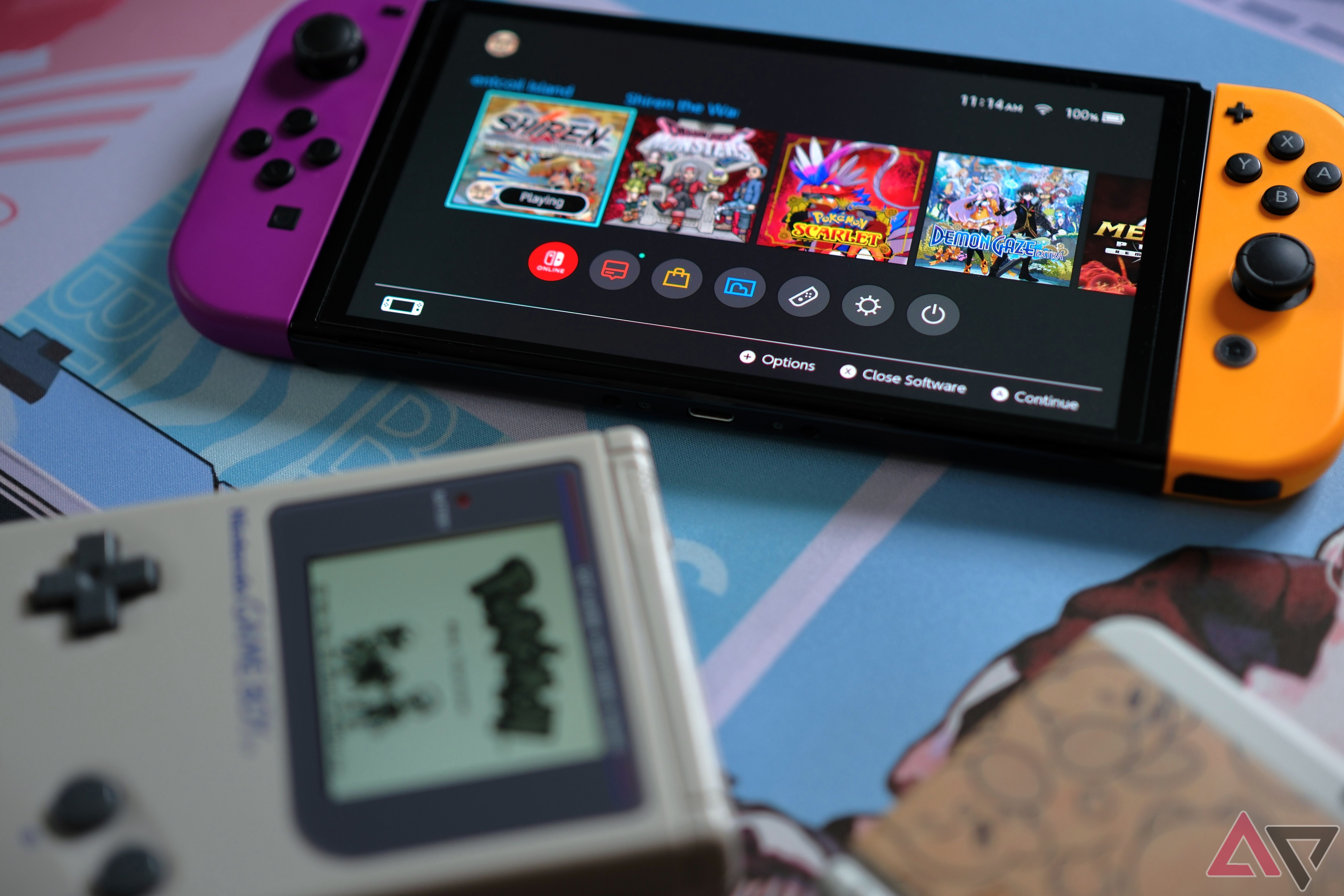 Nintendo Switch laying on colorful deskmat with game boy and 3ds