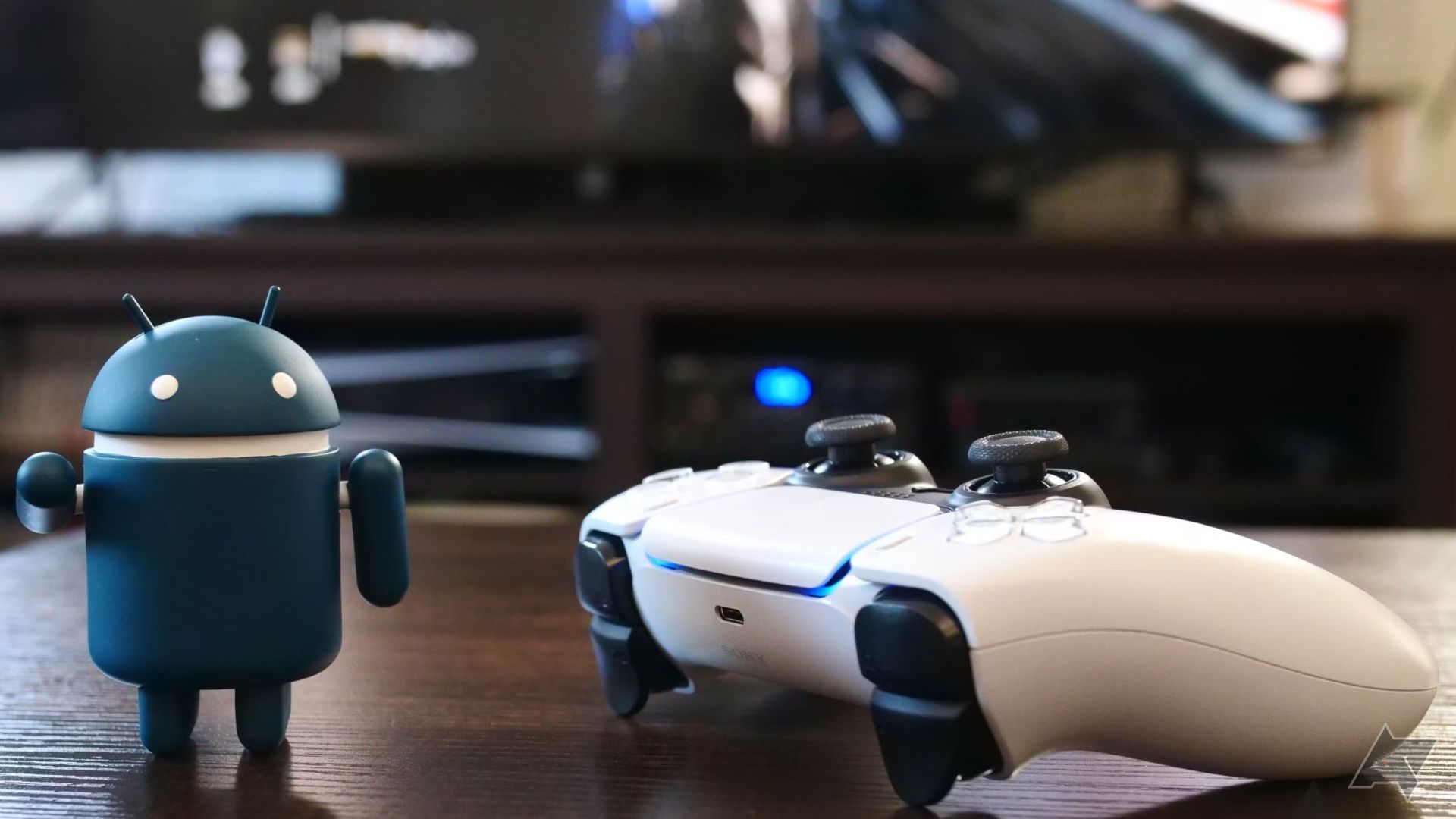 The Android robot stands next to a PS5 game controller