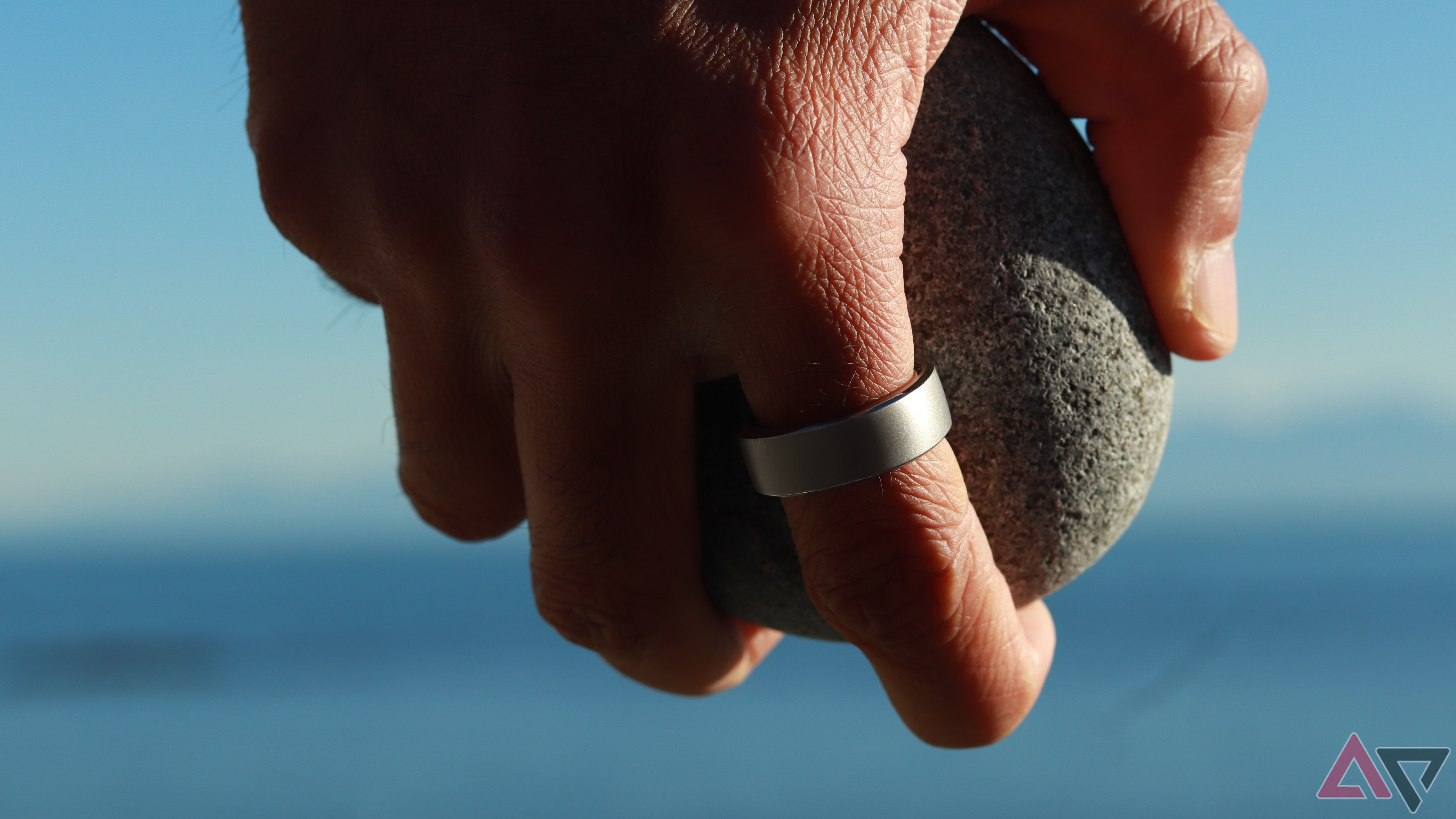 A hand wearing a wisdom ring holding a stone