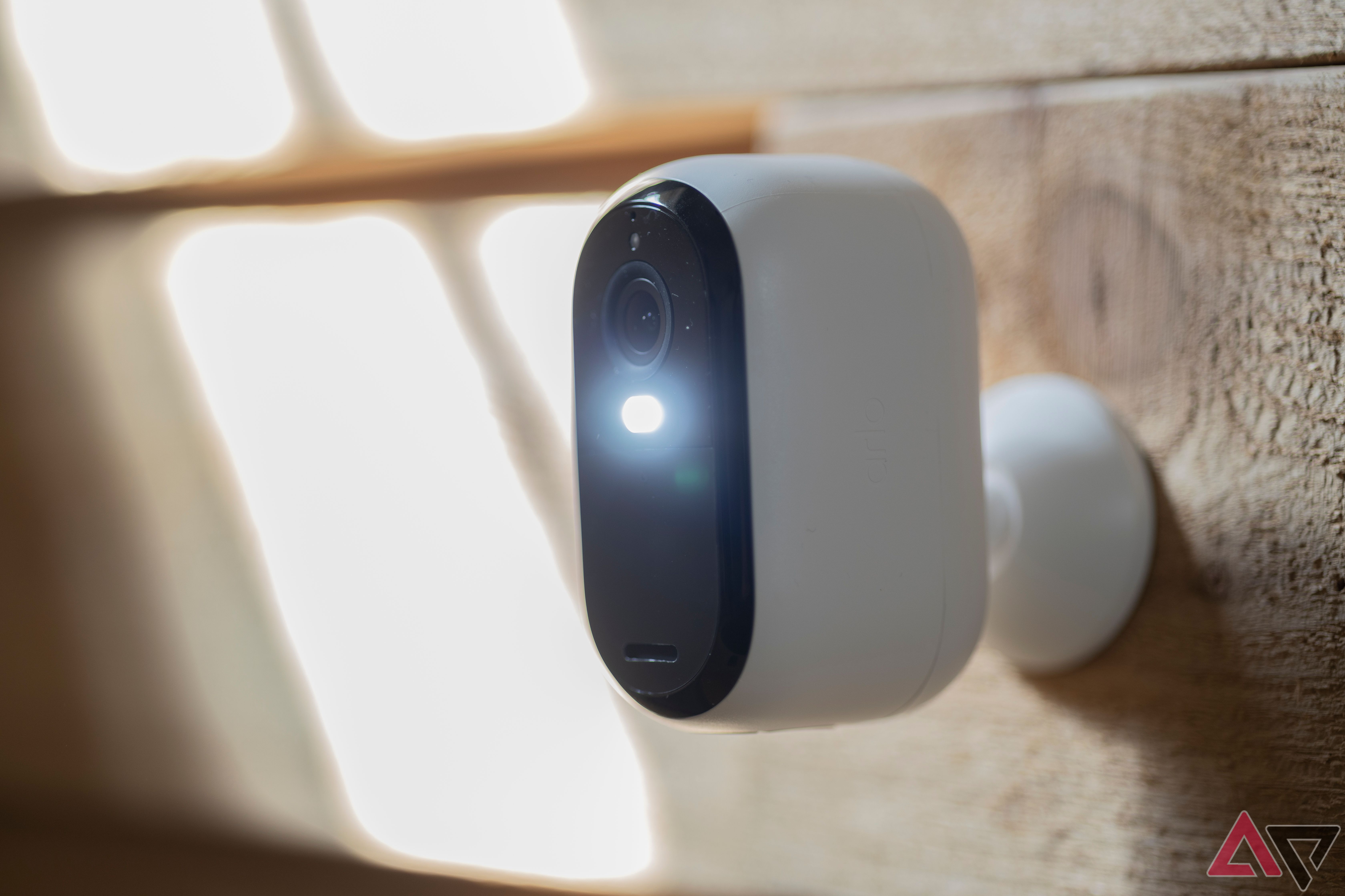 Close up of Arlo Essential Security Camera XL (2K, 2nd Gen) mounted on wall with spotlight on