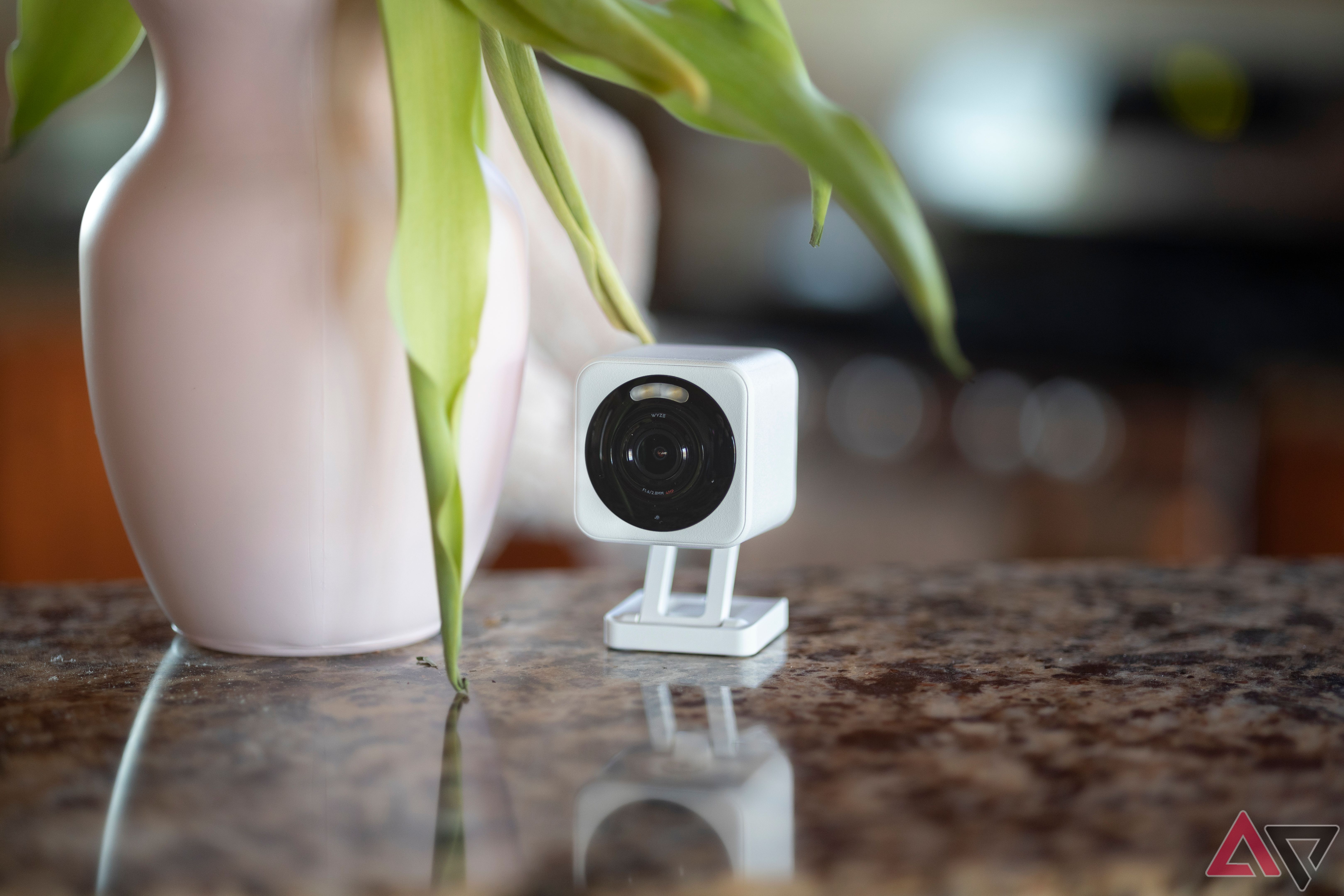 Wyze Cam v4 sitting on granite countertop next to pink vase