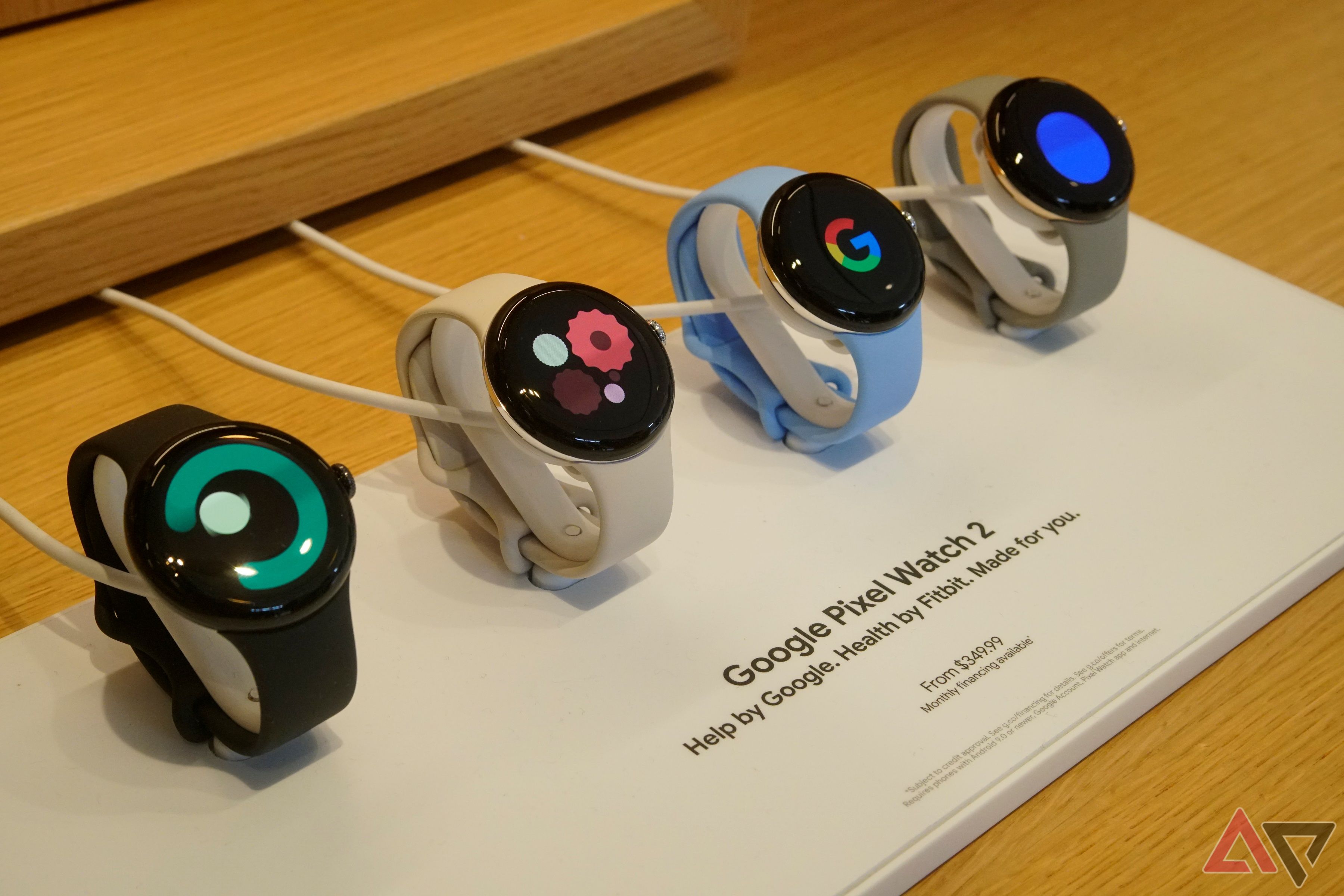 Four Google Pixel Watch 2 units charging on a retail table.