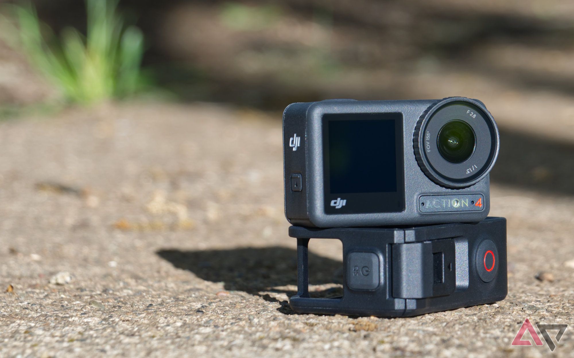 DJI Osmo Action 4 stacked on shock-resistant case with long shadows on concrete and grass in the background