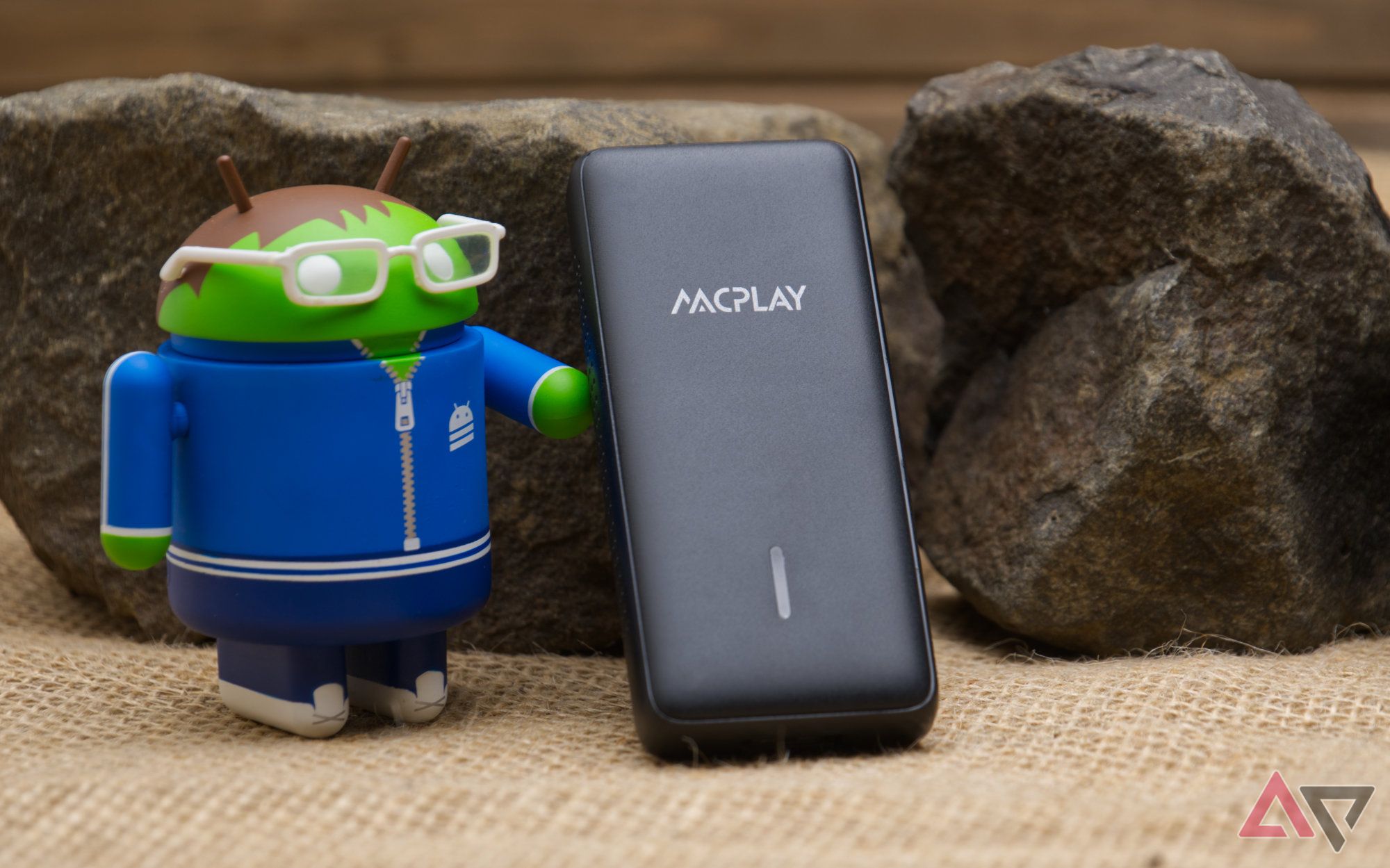 AACPlay wireless adapter leaning against a rock and next to an android figure with glasses