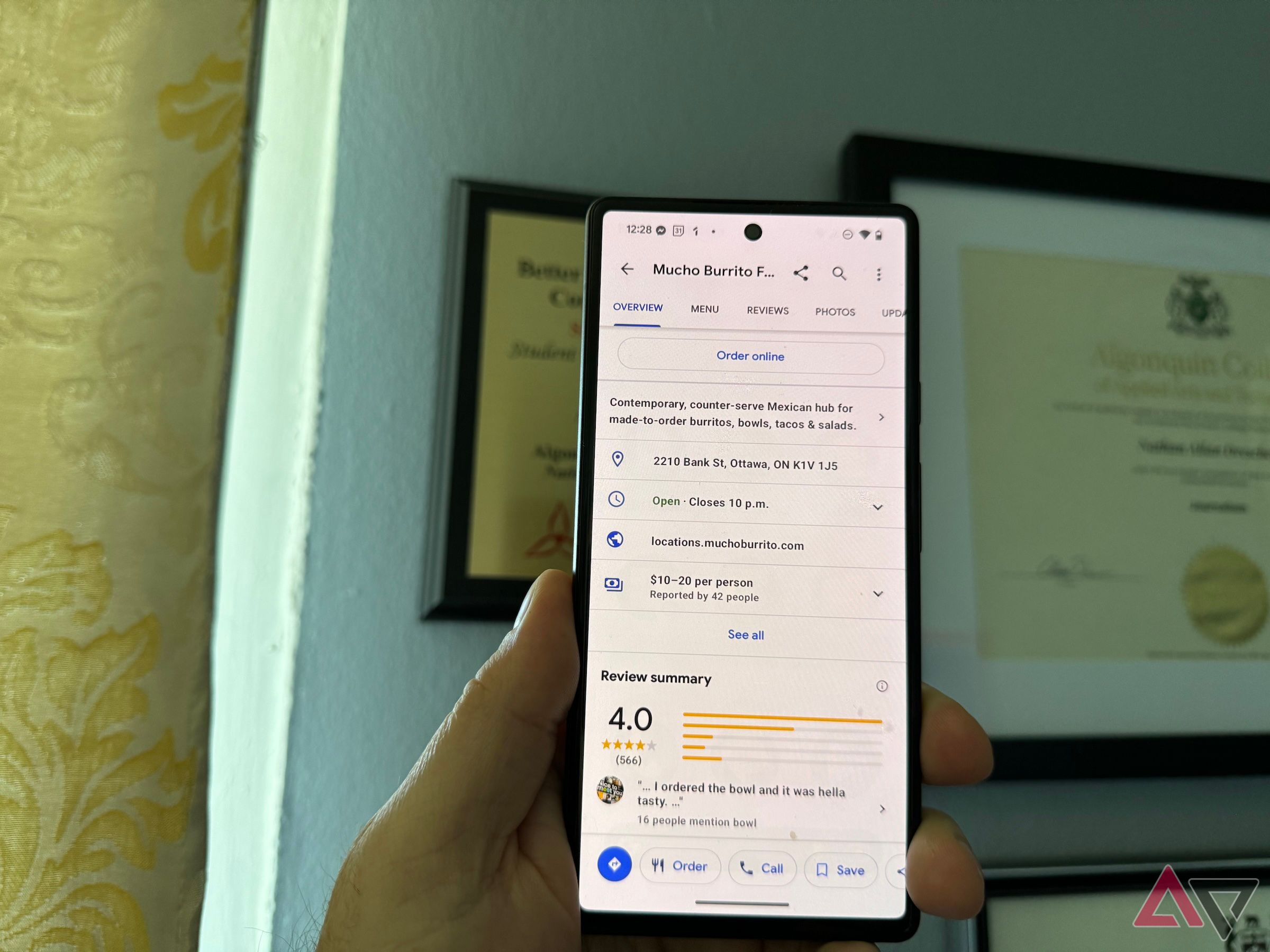 A hand holding a Pixel 6 with Google Maps showing user reviews for a burrito restaurant in Ottawa.