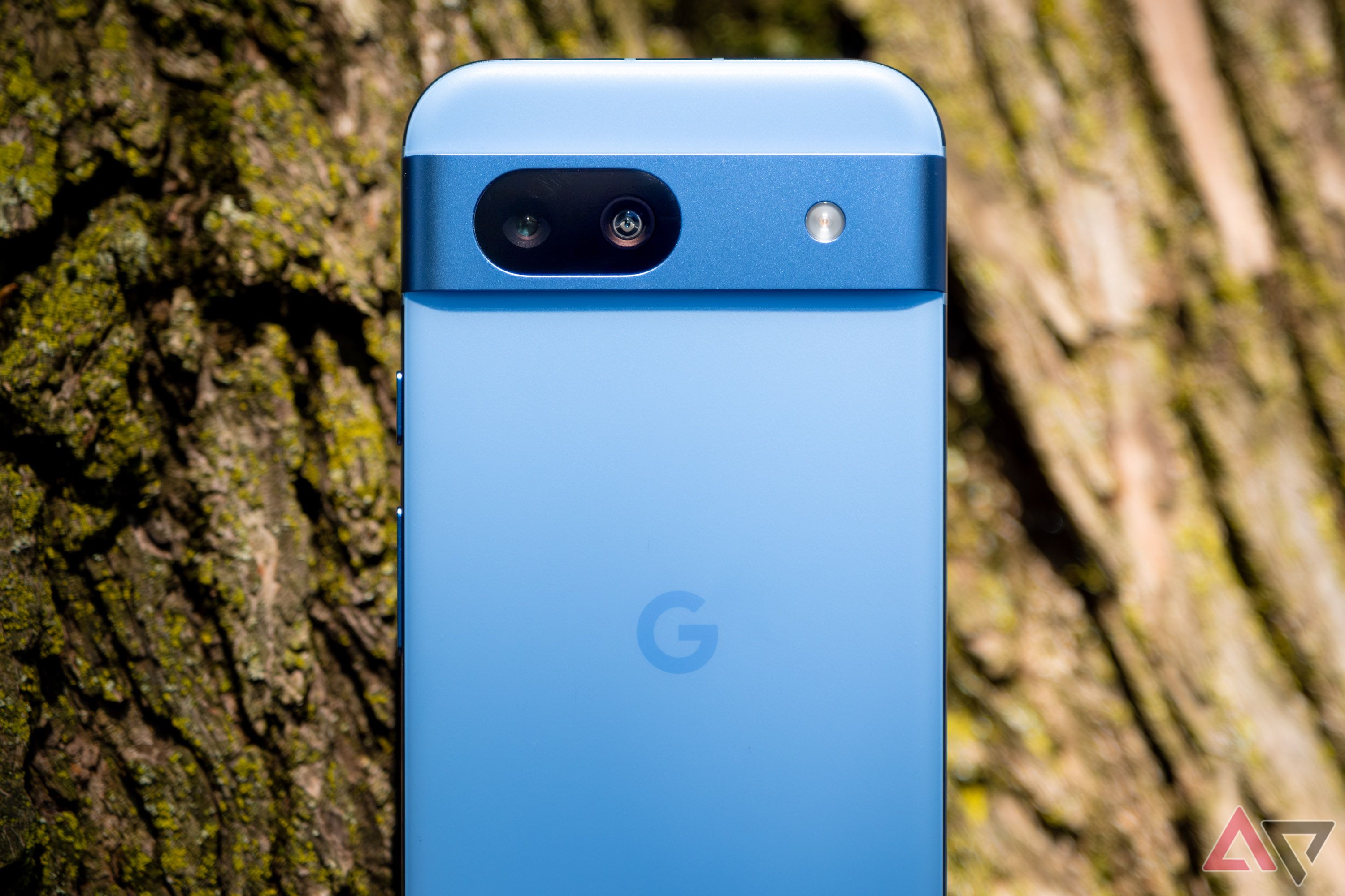 A blue smartphone in front of a tree