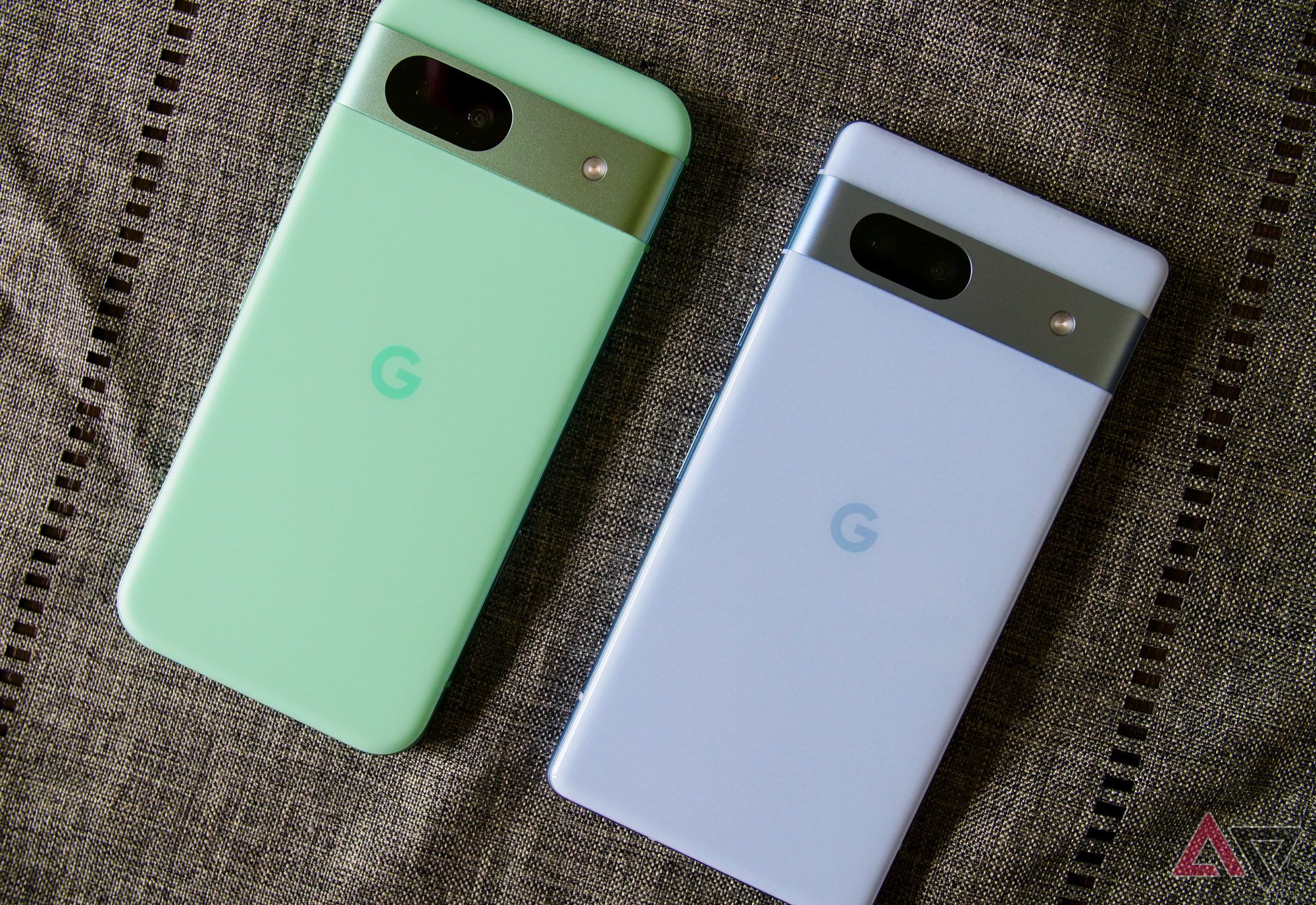 The Pixel 8a and Pixel 7a lying on gray fabric.