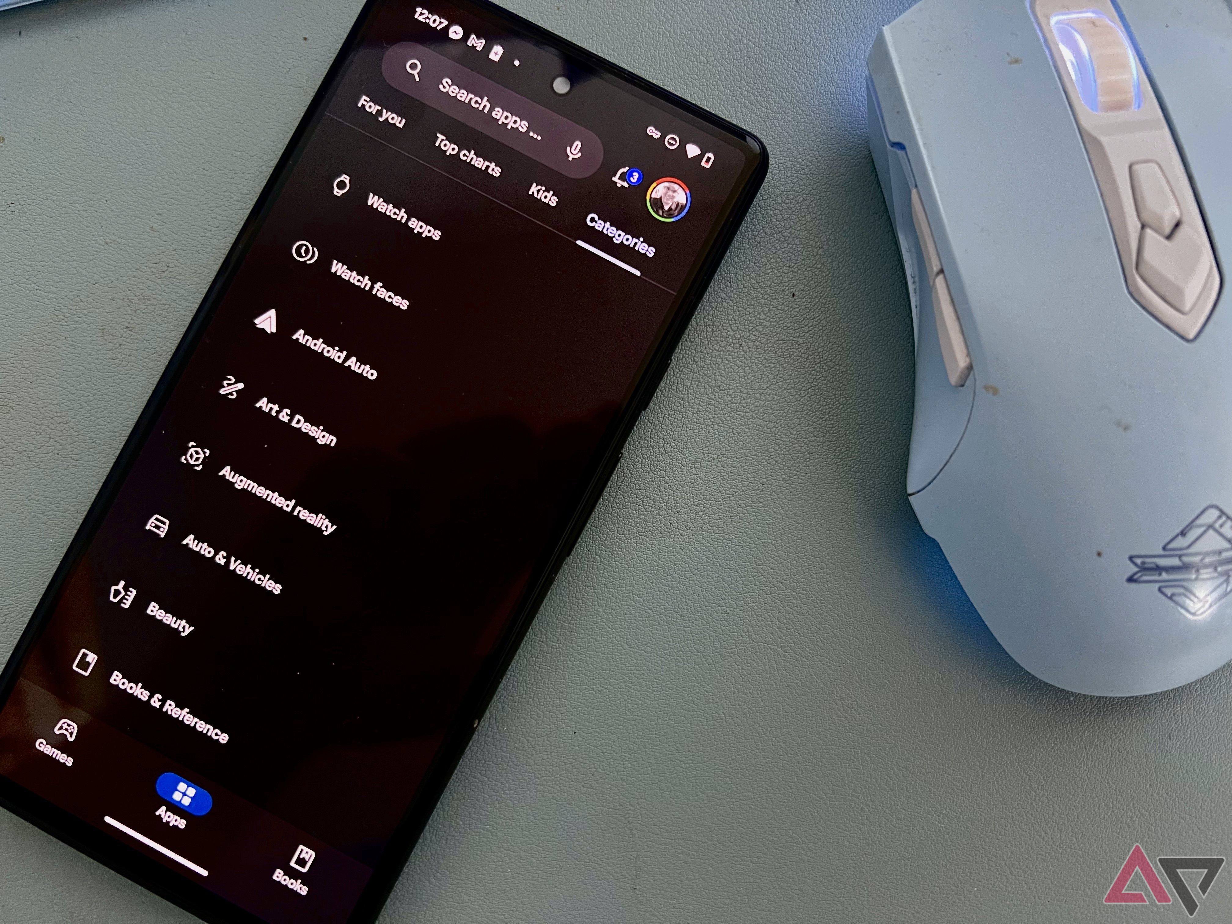 The Google Play Store on a Pixel 6 laying next to a blue mouse on a desk. 