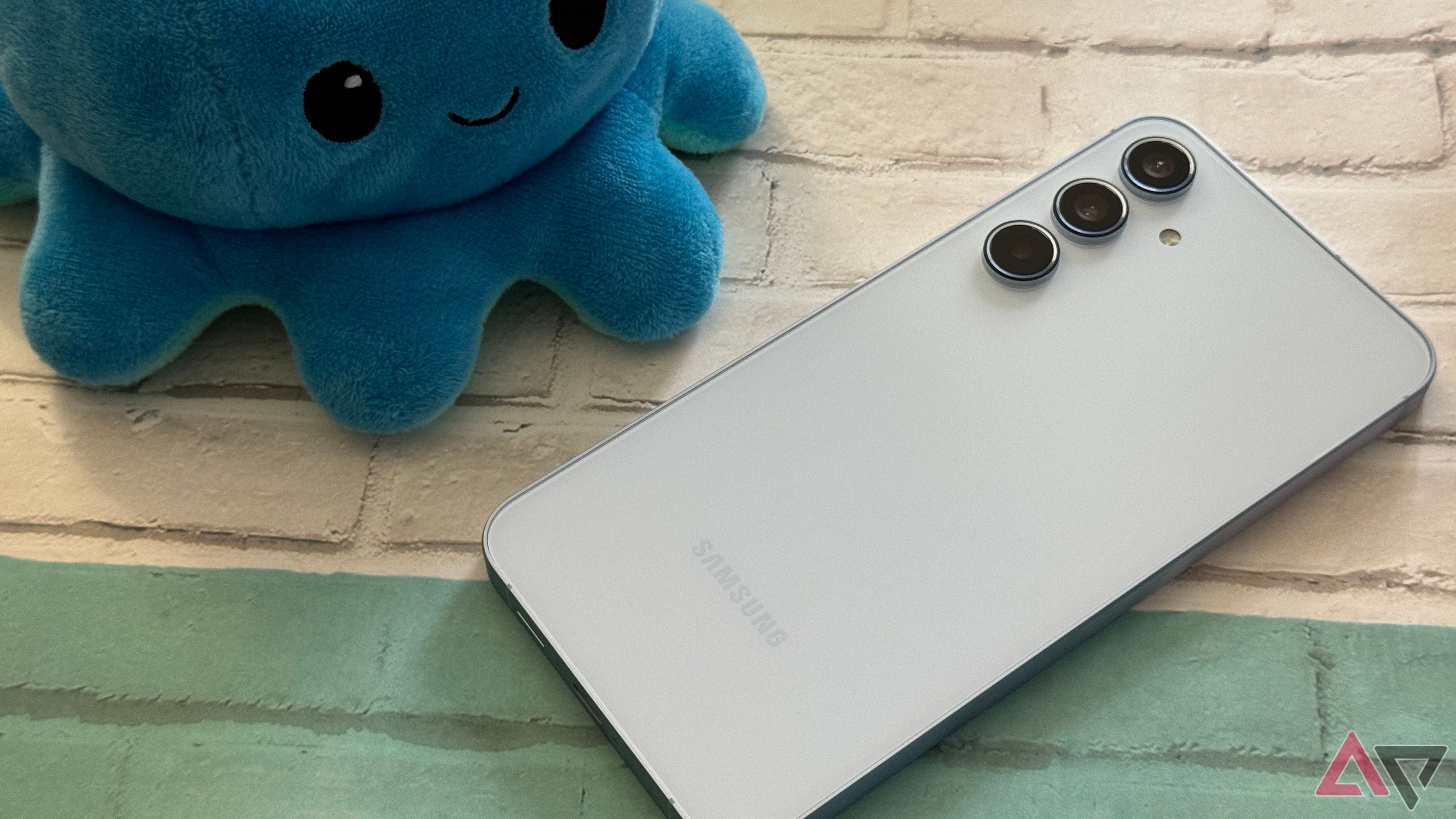 Samsung Galaxy A55 in blue laying against a background with a plushie