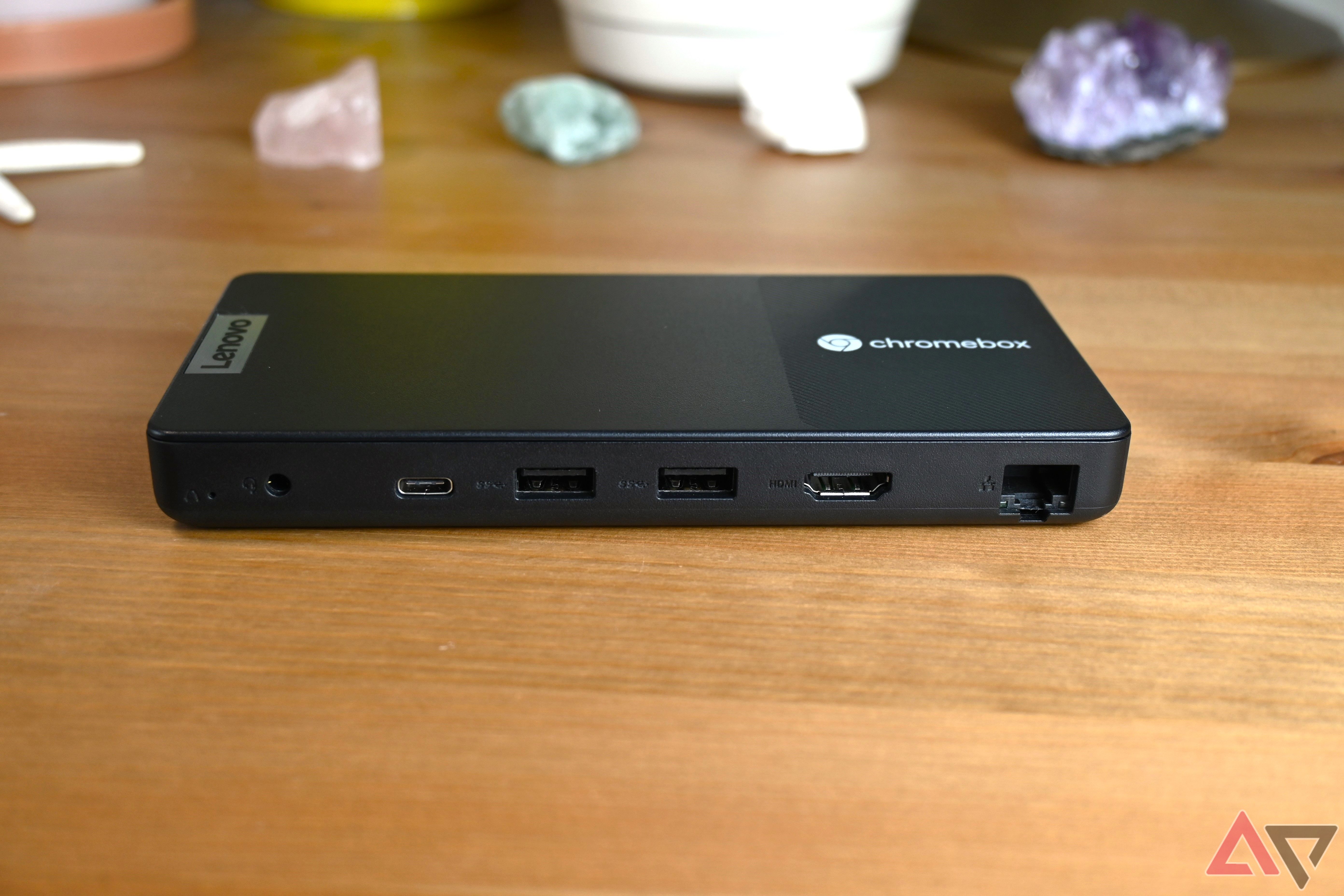 Lenovo Chromebox Micro on a light brown table with various colored stones in the background