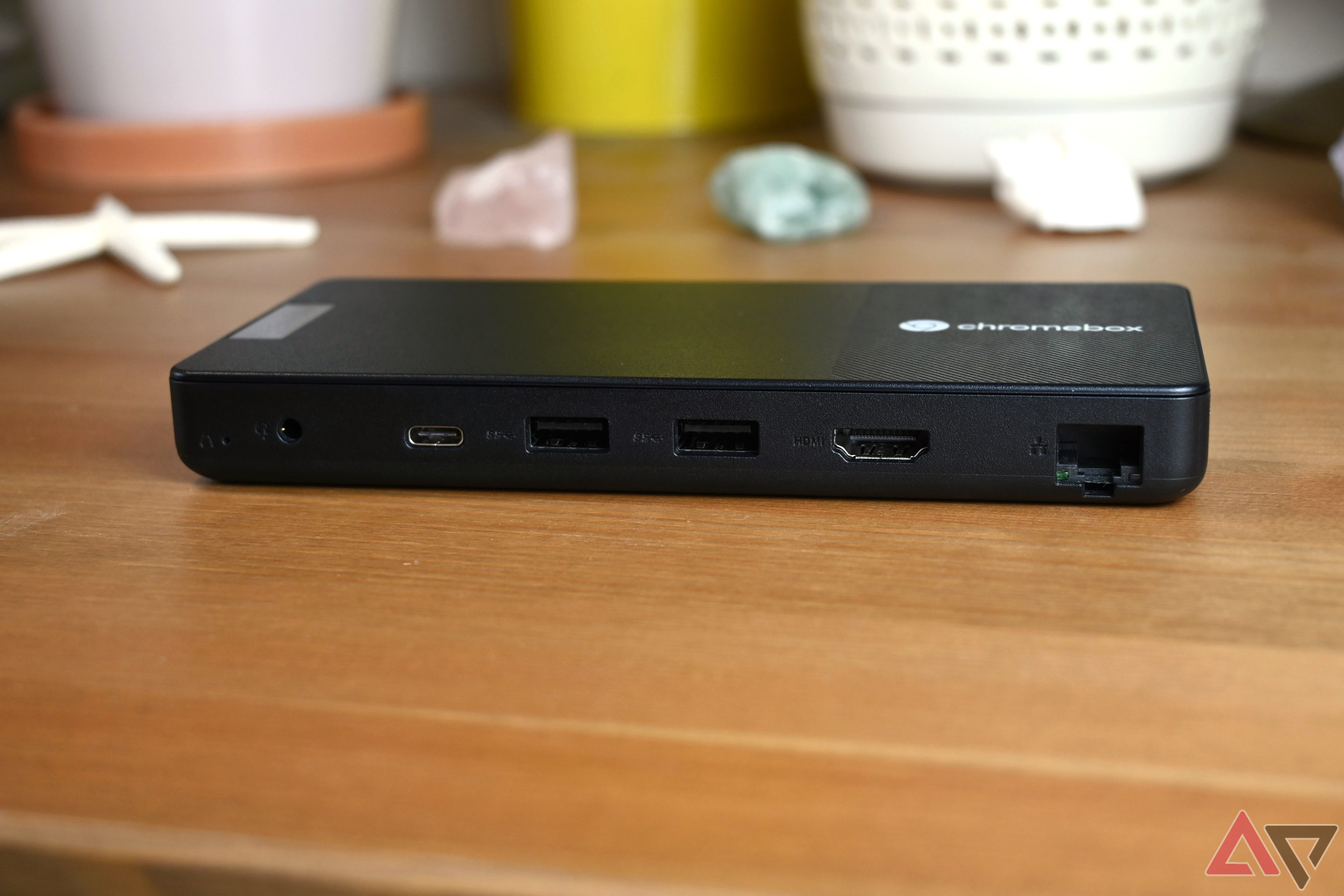 Lenovo Chromebox Micro on a light wooden table showing its selection of ports with colored rocks in the background