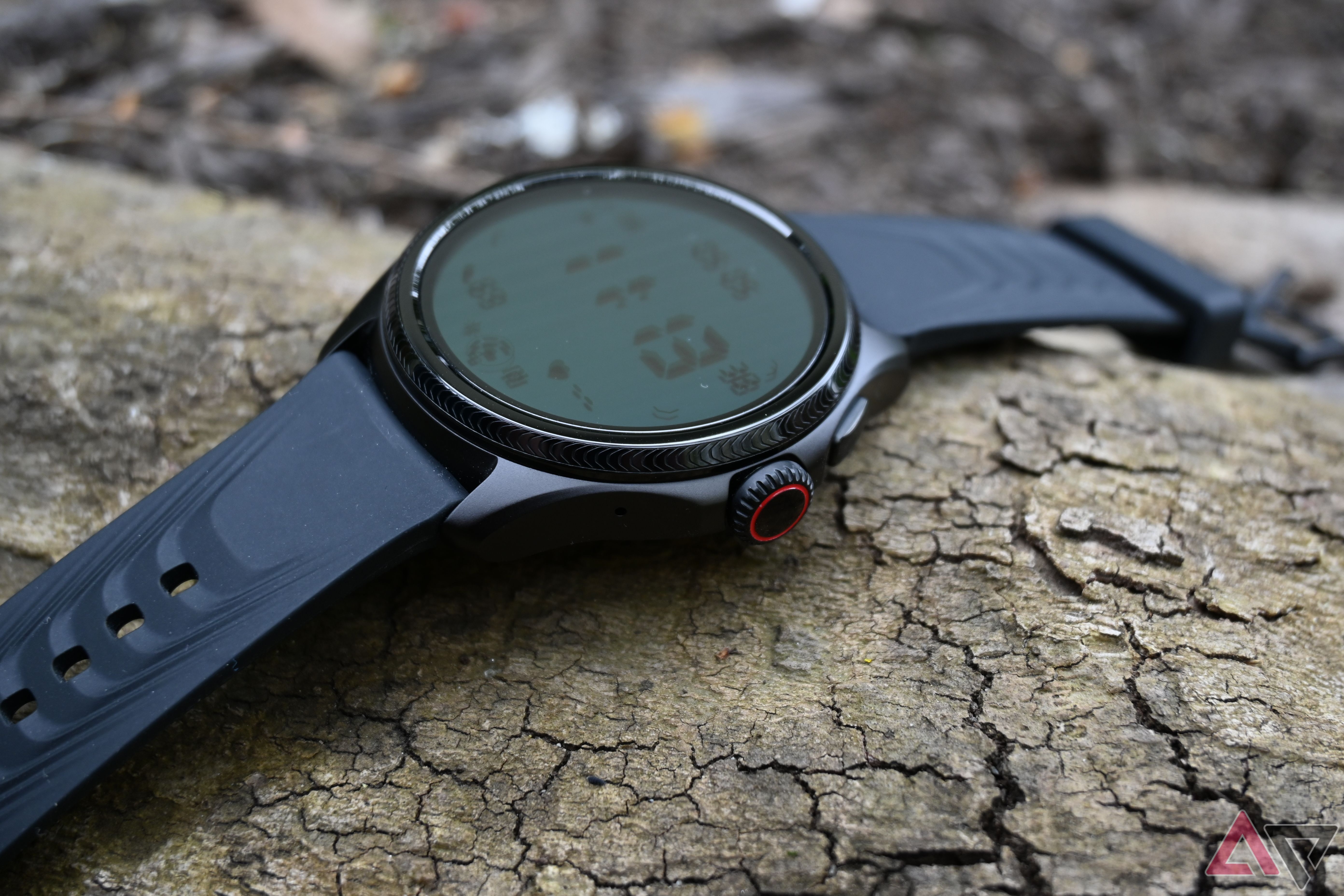 Mobvoi TicWatch Pro 5 Enduro showing its right side and the display while lying on a log.