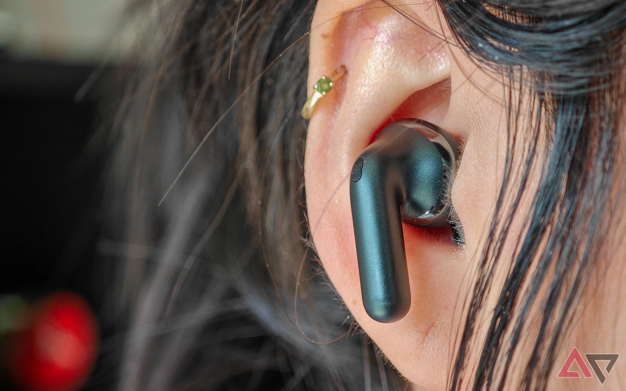 The Moto Buds+ in black with a single earbud shown in a woman's ear