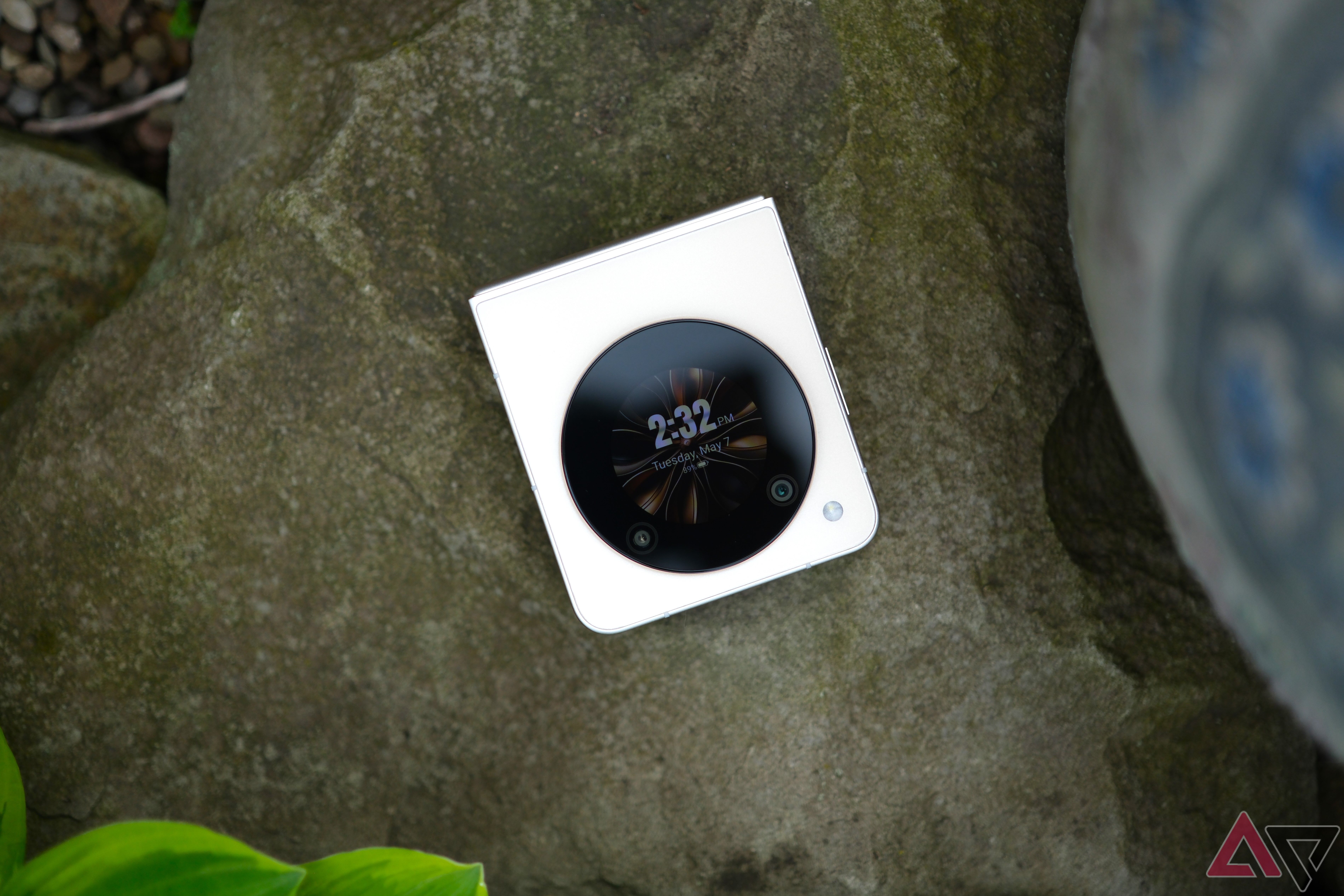 Nubia Flip 5G laying closed on rock with circular screen facing camera with clock on screen