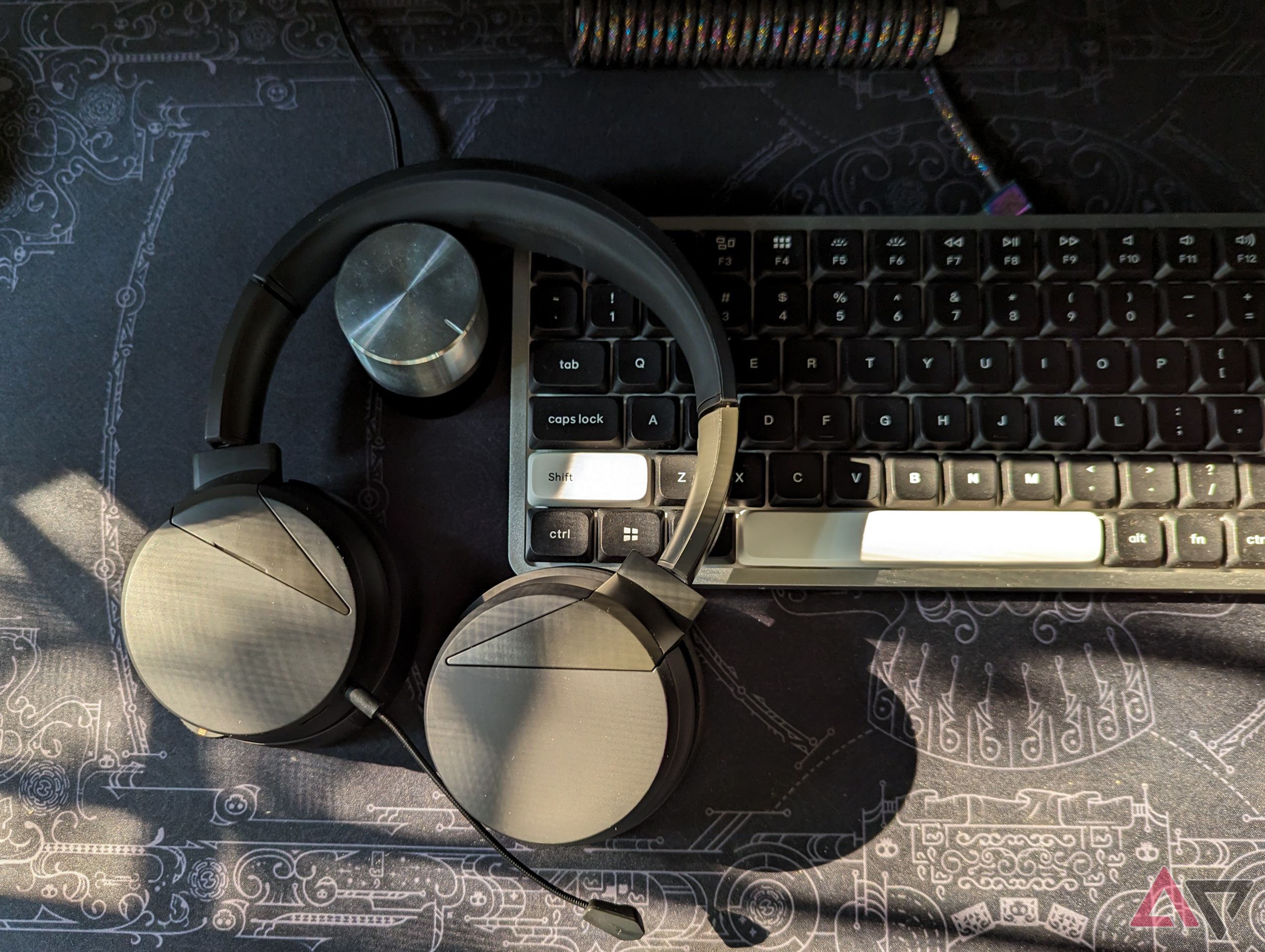 Headphones kept face down on a black sunlit deskmat