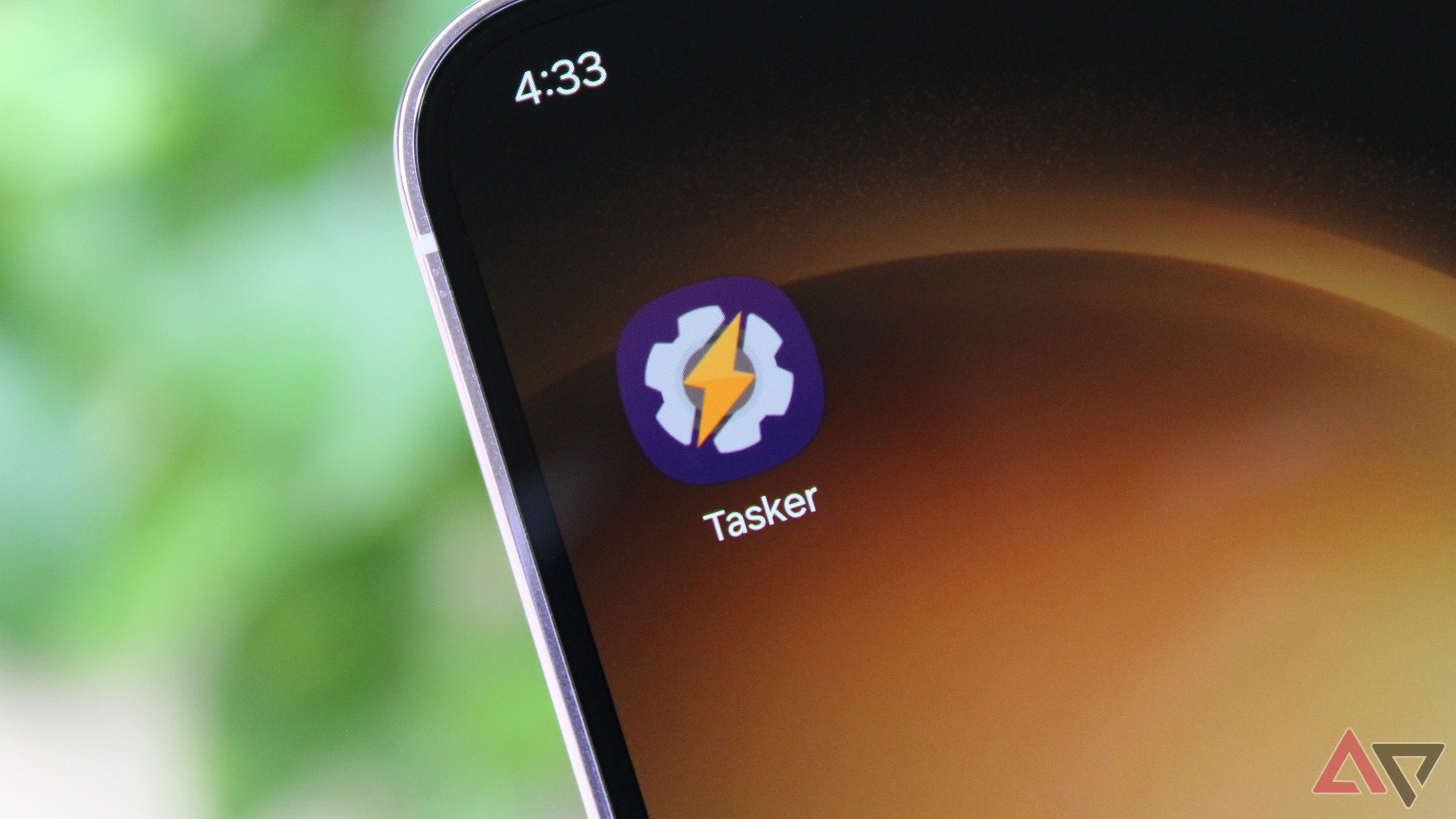 Photo of the Tasker app's icon on a phone's home screen, close-cropped against a green background.