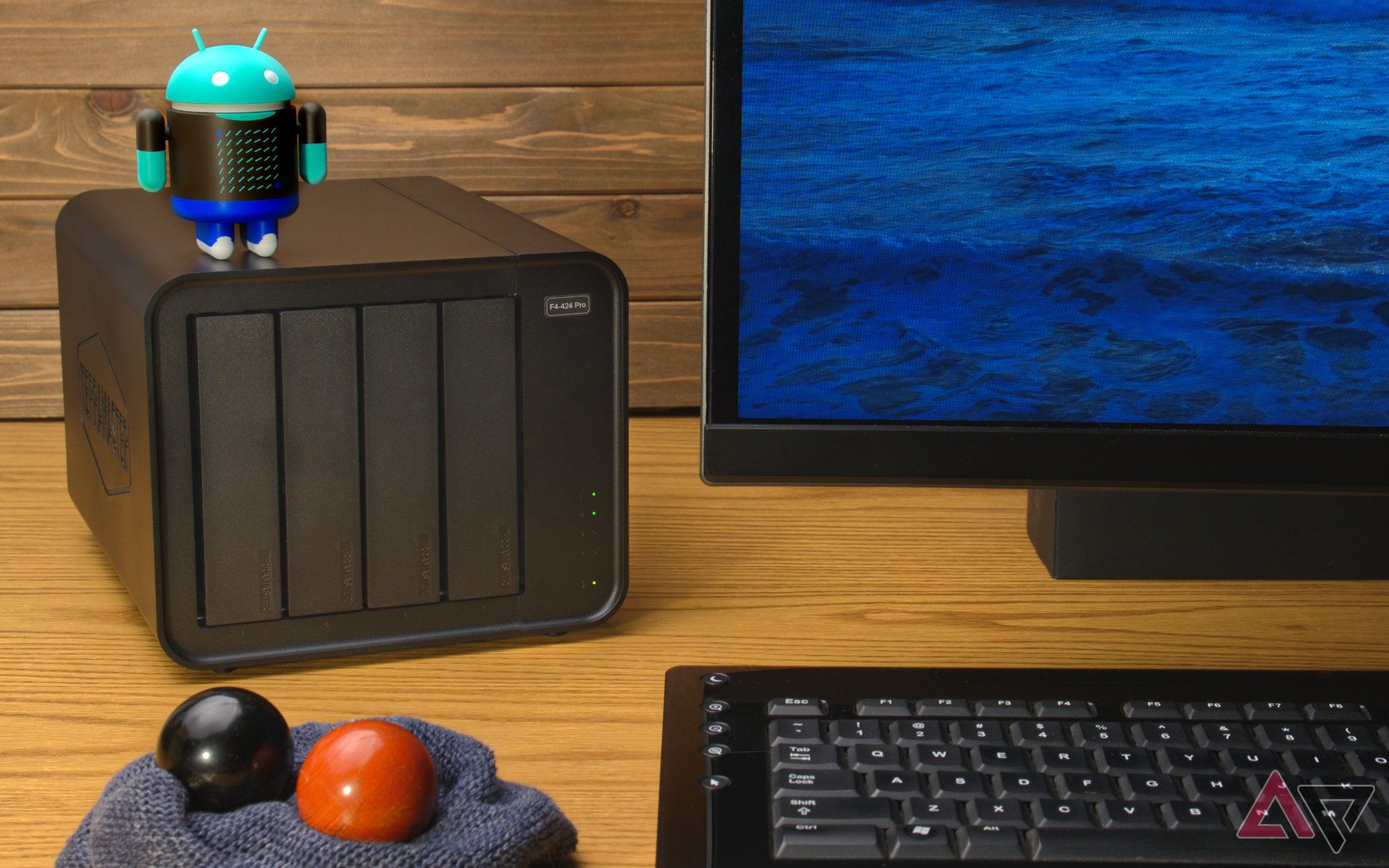 Terramaster F4-424 Pro and android figure sitting on a desk next to a keyboard, monitor, and baoding balls