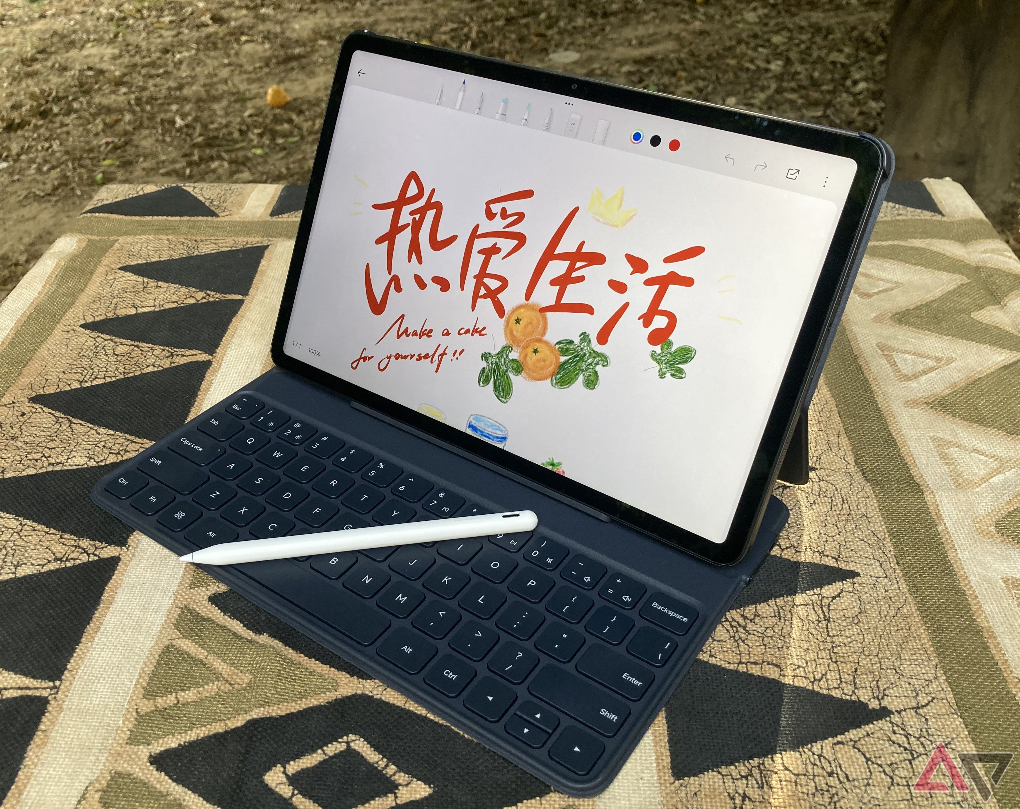 A picture of the Redmi Pad Pro in its keyboard case with the stylus on the keys and a sample Mi Canvas image on the screen