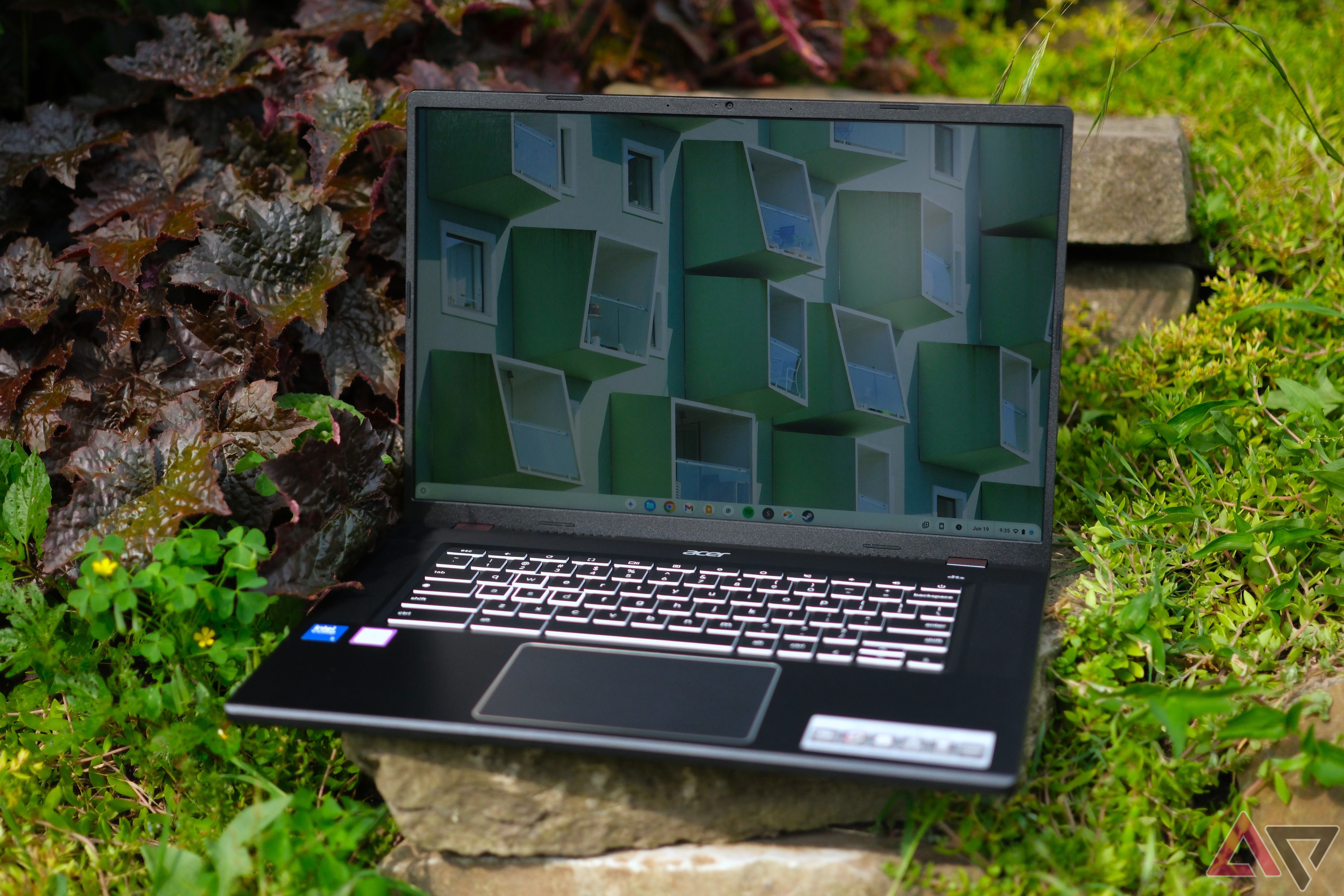 Acer Chromebook Plus 516 GE (2024) sitting on rock with plants around with the lid open and screen on