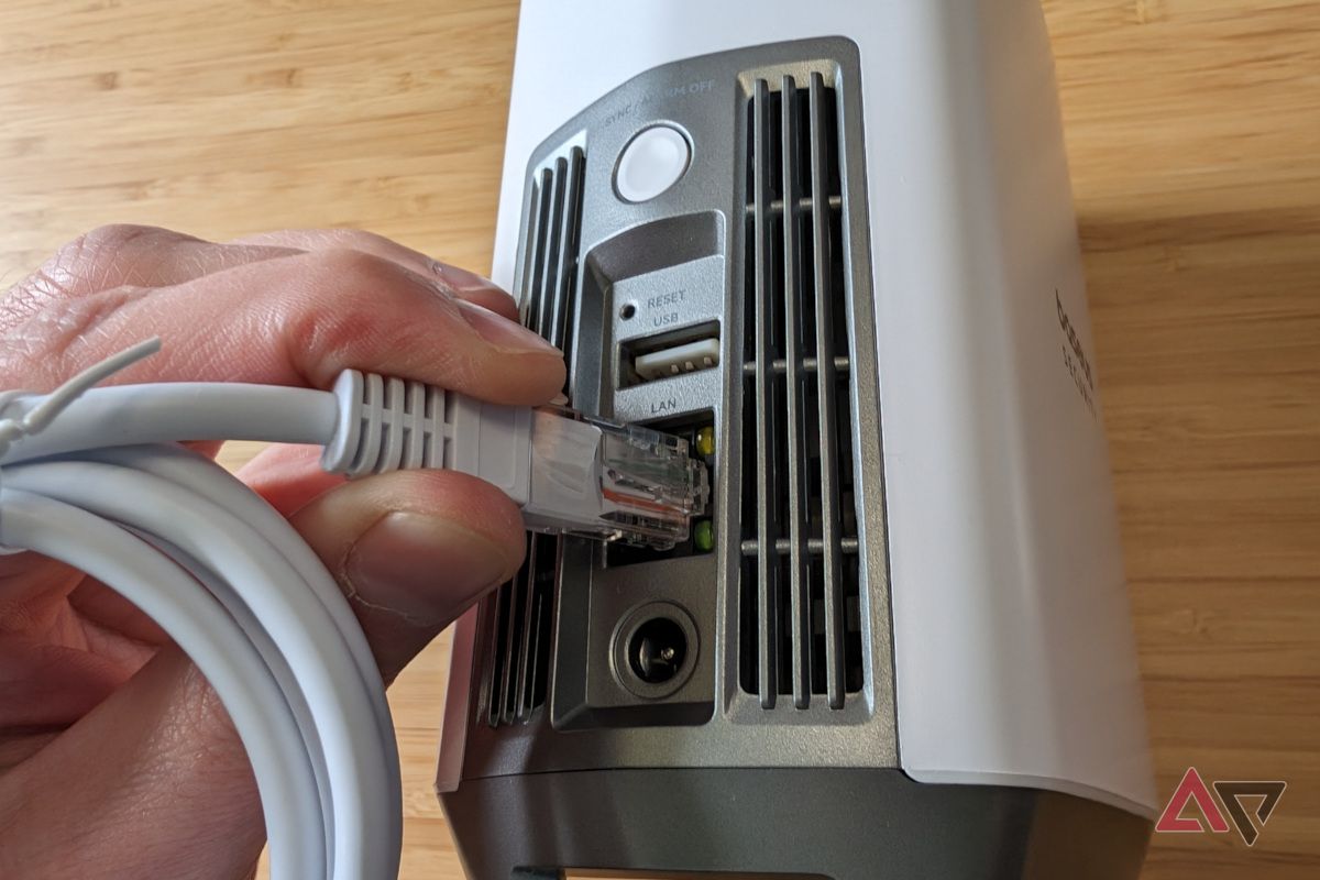 Baseus Homestation rear ports with hand connecting an ethernet cable