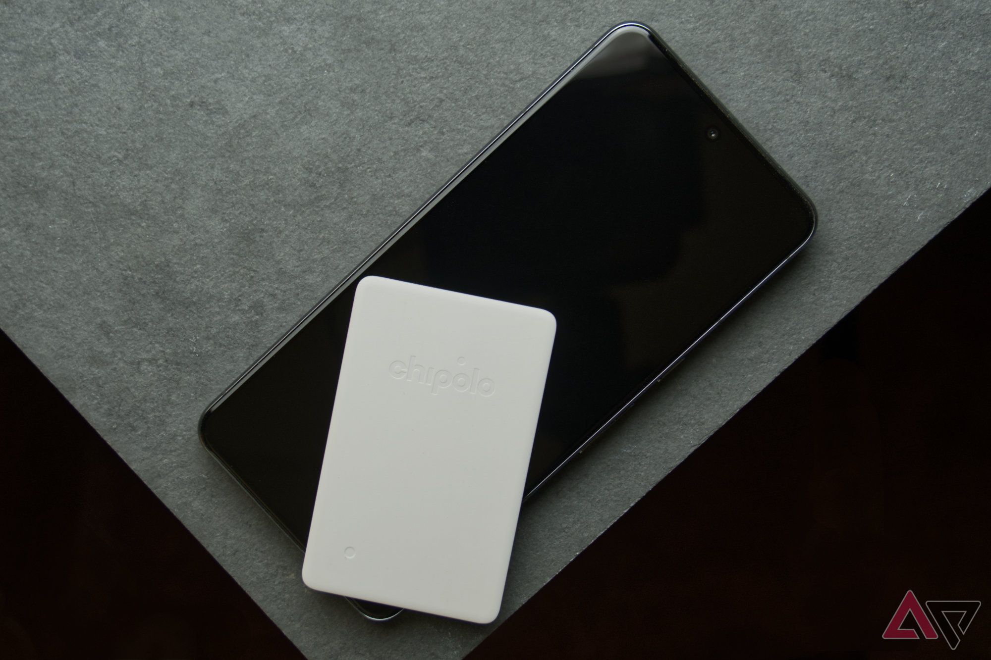 Chipolo CARD Point on a smartphone resting on a gray tile