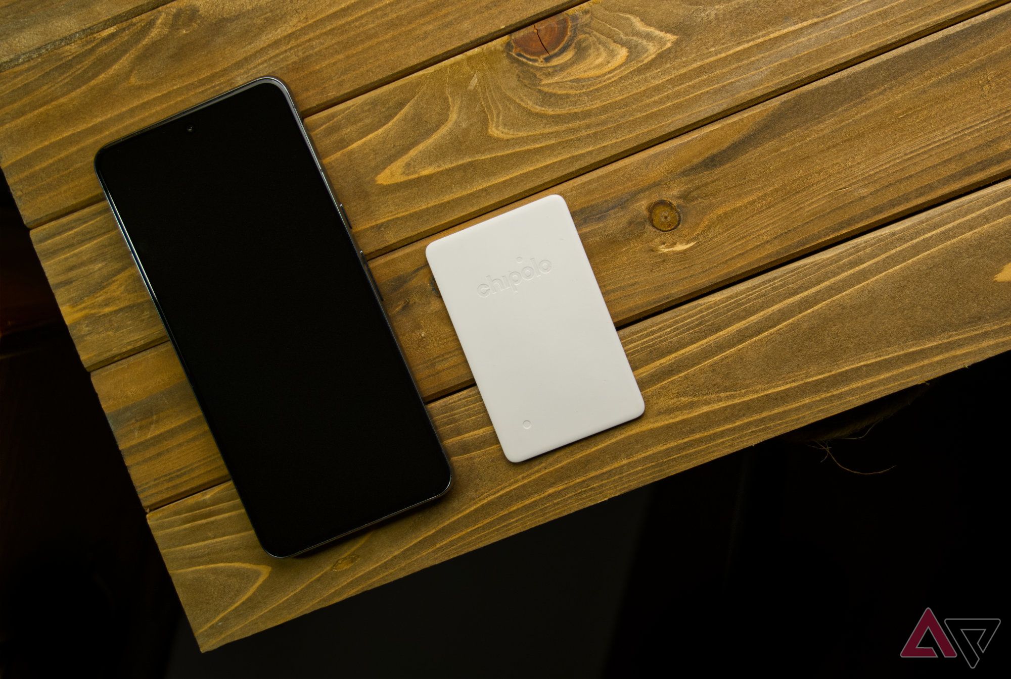 Chipolo CARD Point and a smartphone on a wooden plank