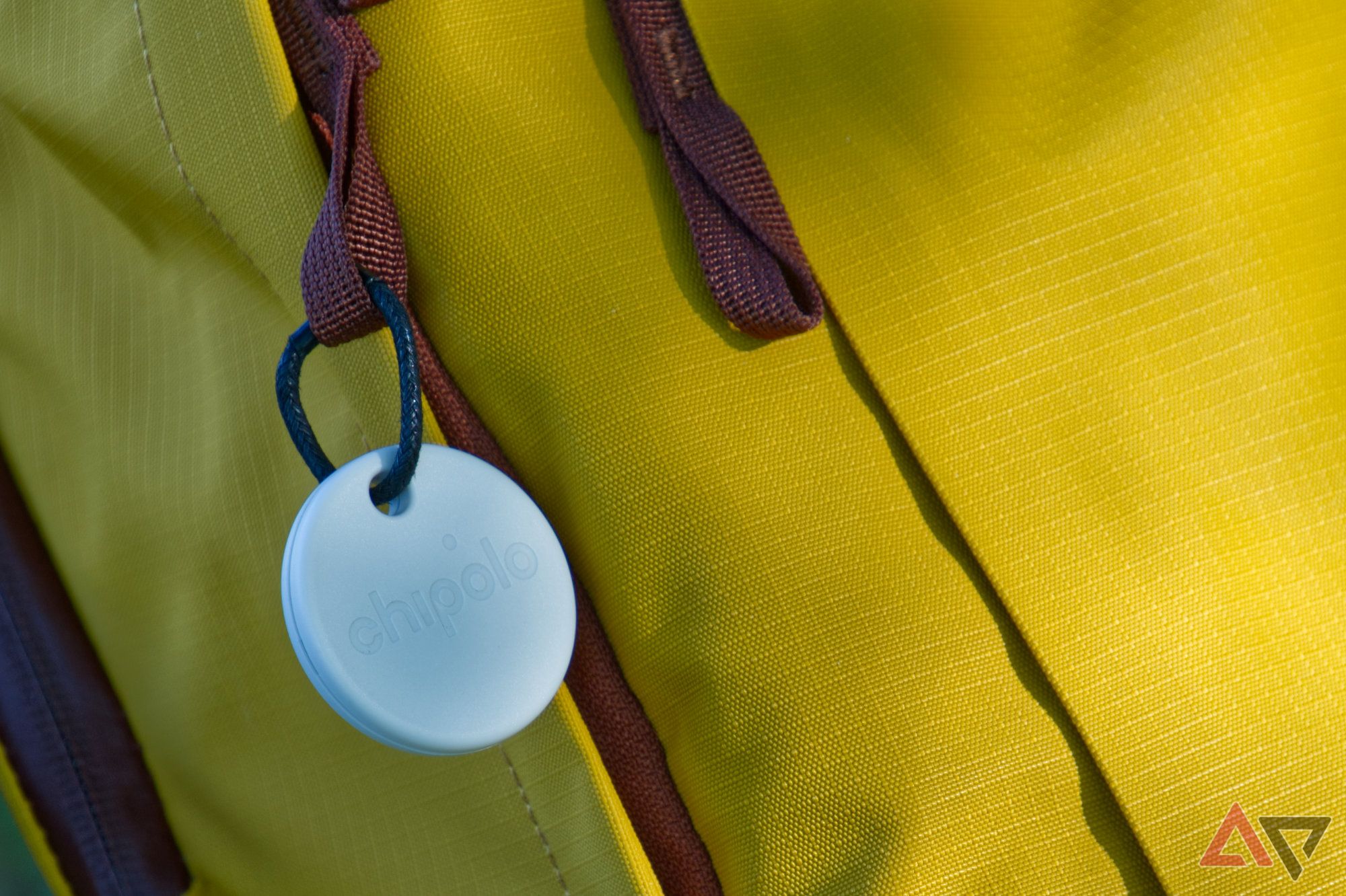 Closeup of a Chipolo One Point tag attached to a yellow backpack