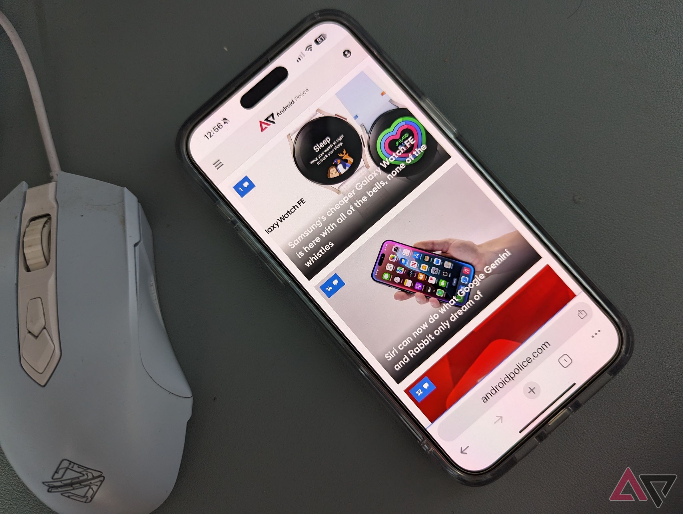 Google Chrome on an iPhone 15 Pro Max laying on a desk next to a mouse, showing the bottom toolbar