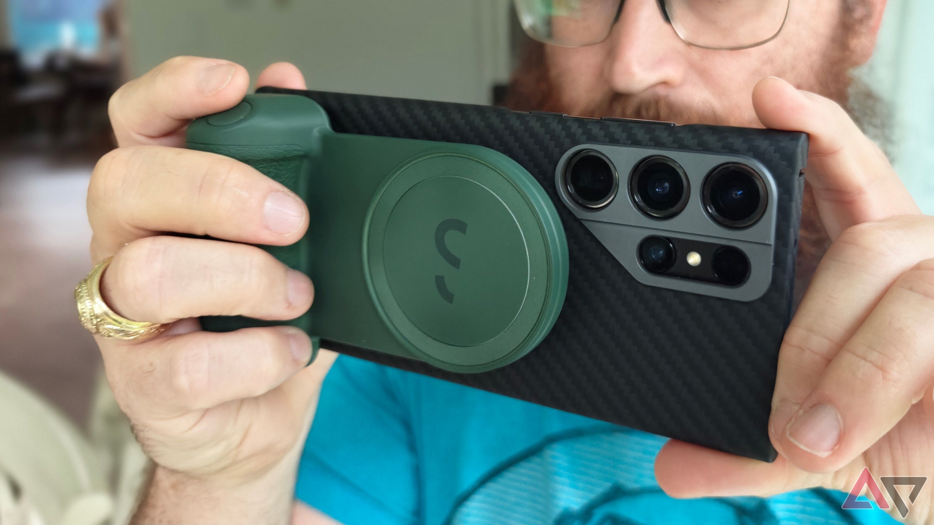 ShiftCam SnapGrip being used on a black phone by a man in a blue shirt with a beard wearing glasses