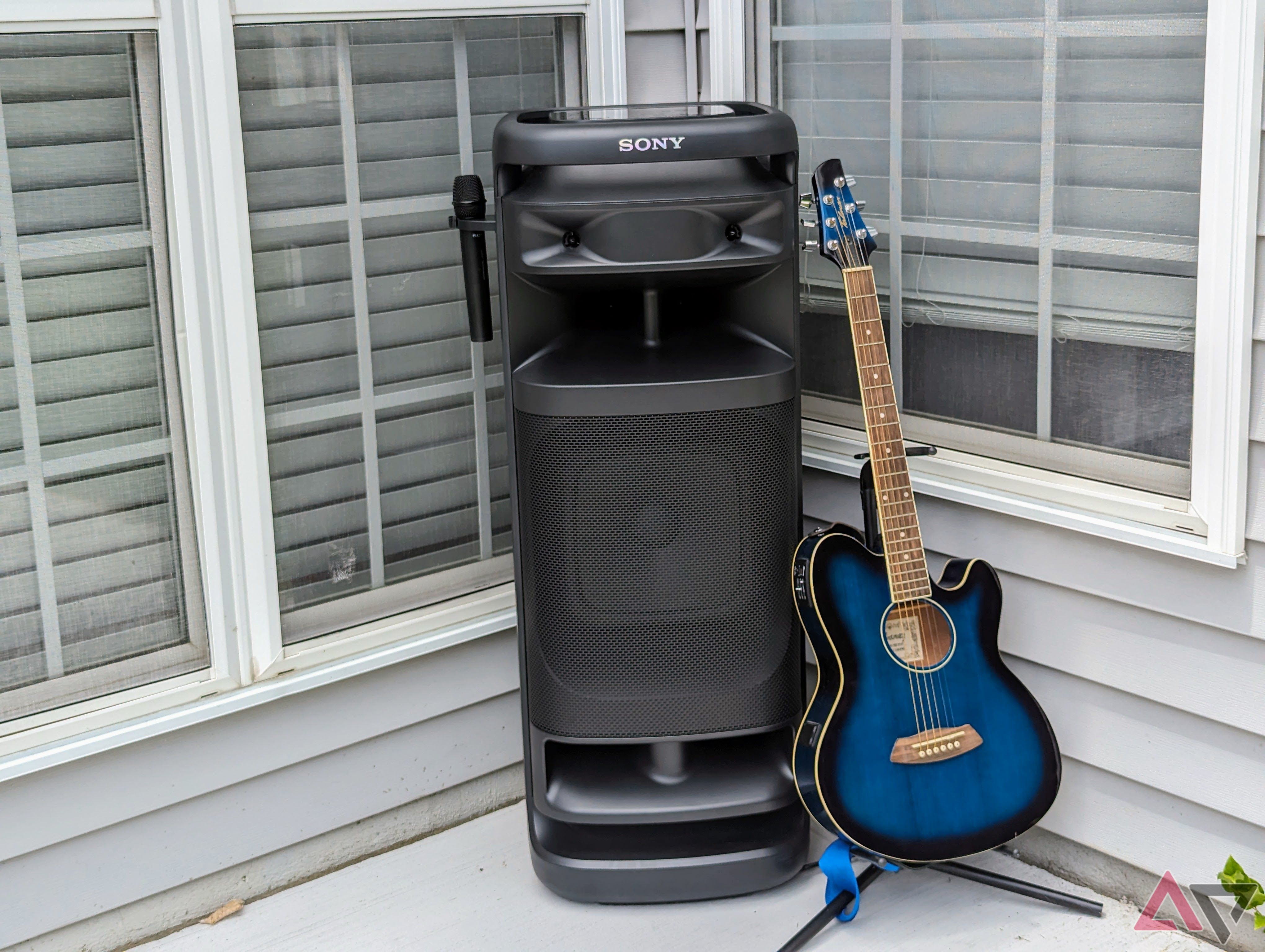 Sony Ult Power 10 tower outside next to blue acoustic guitar on a stand