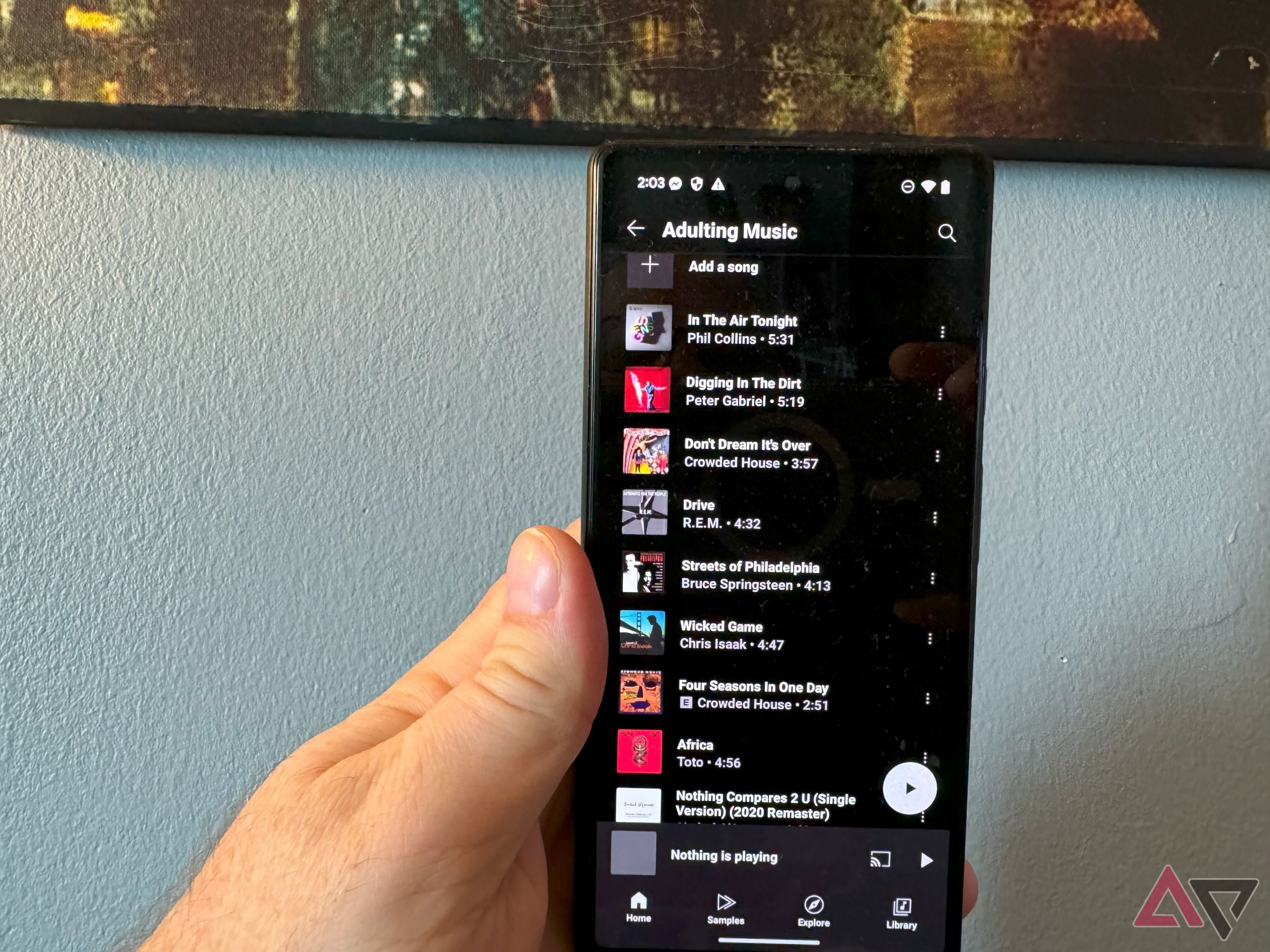 A YouTube Music playlist on a Pixel phone in a man's hand.