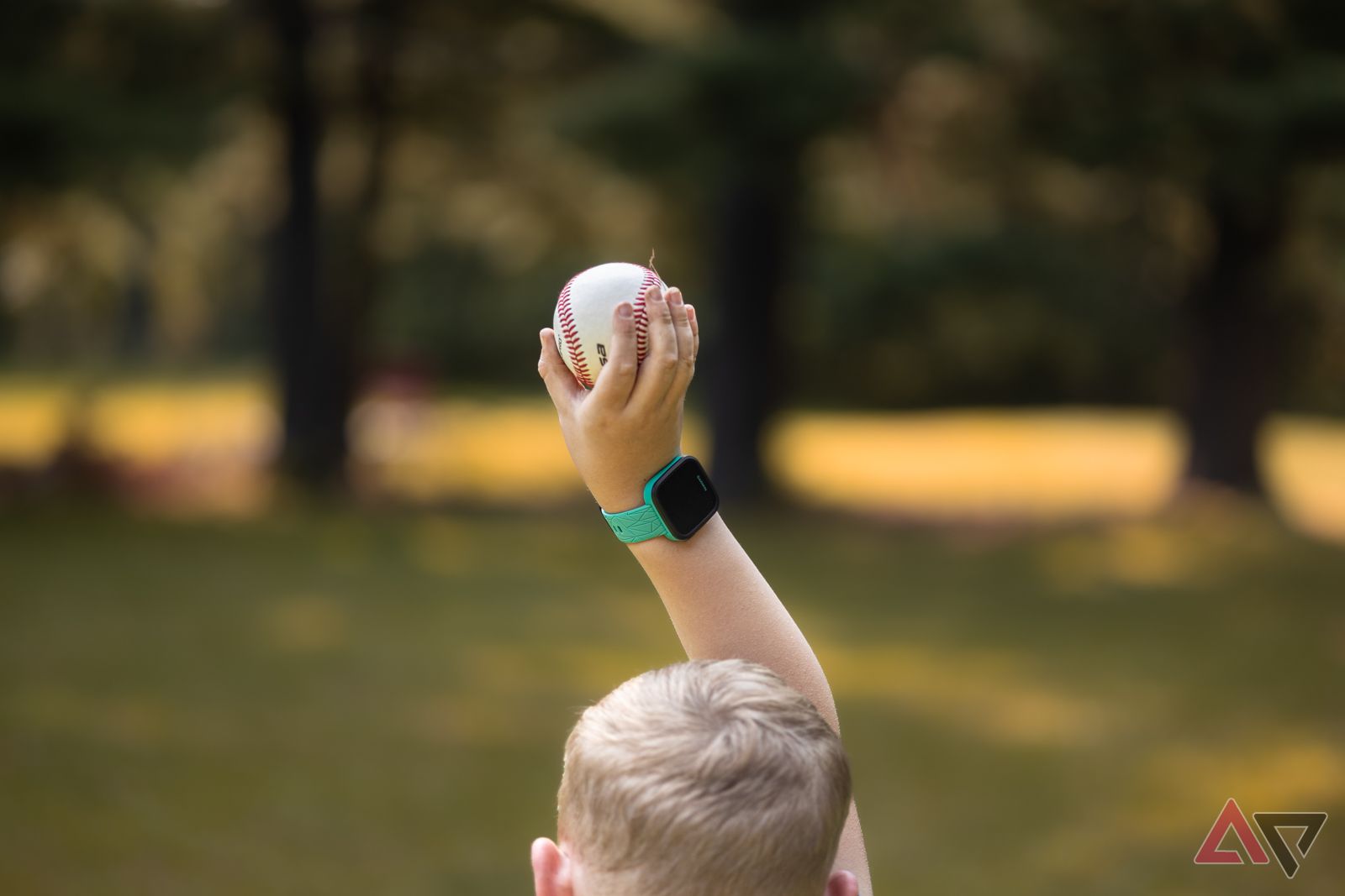 Child holding up baseball while wearing Garmin Bounce smartwatch