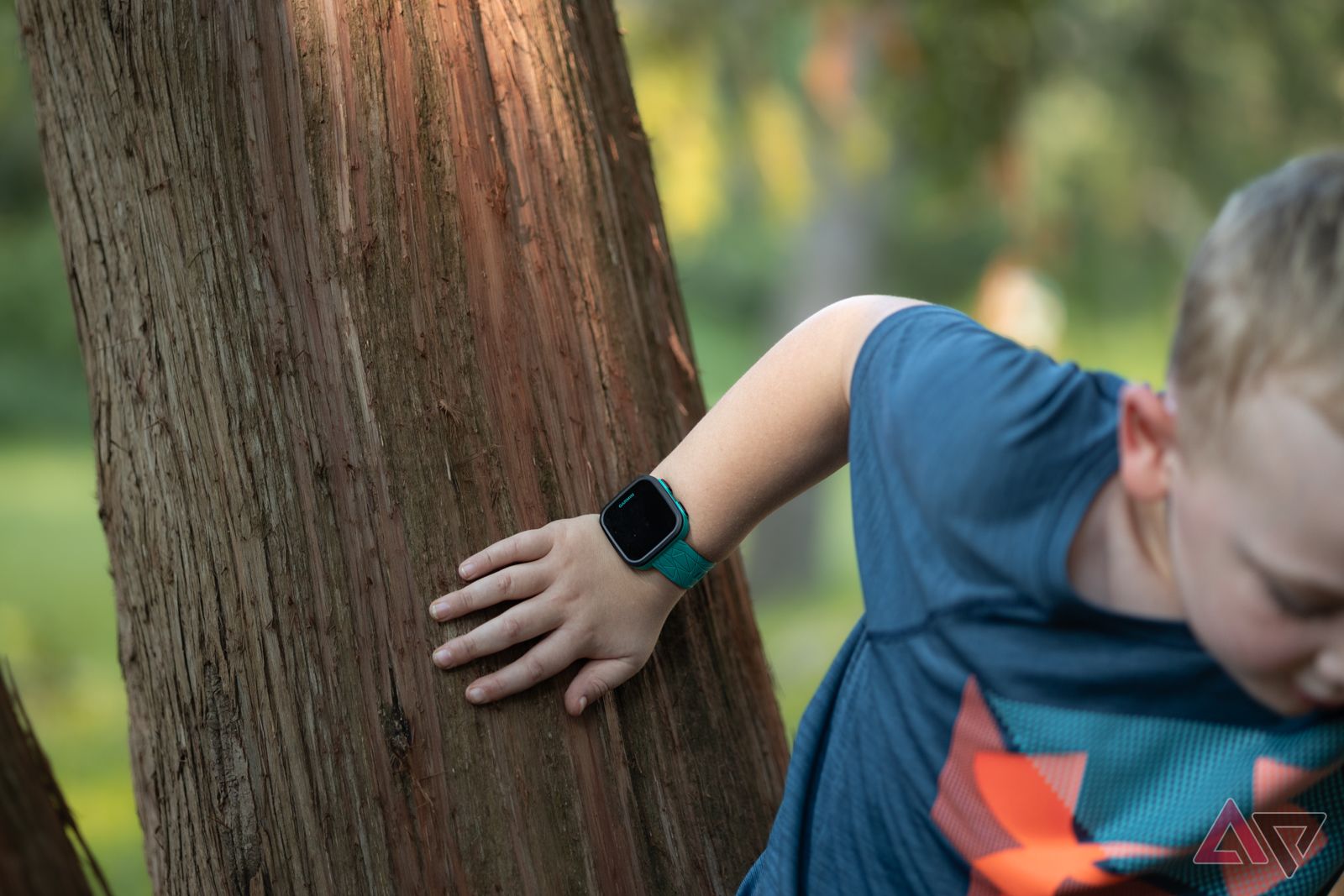 Child climbing tree wearing Garmin Bounce smartwatch