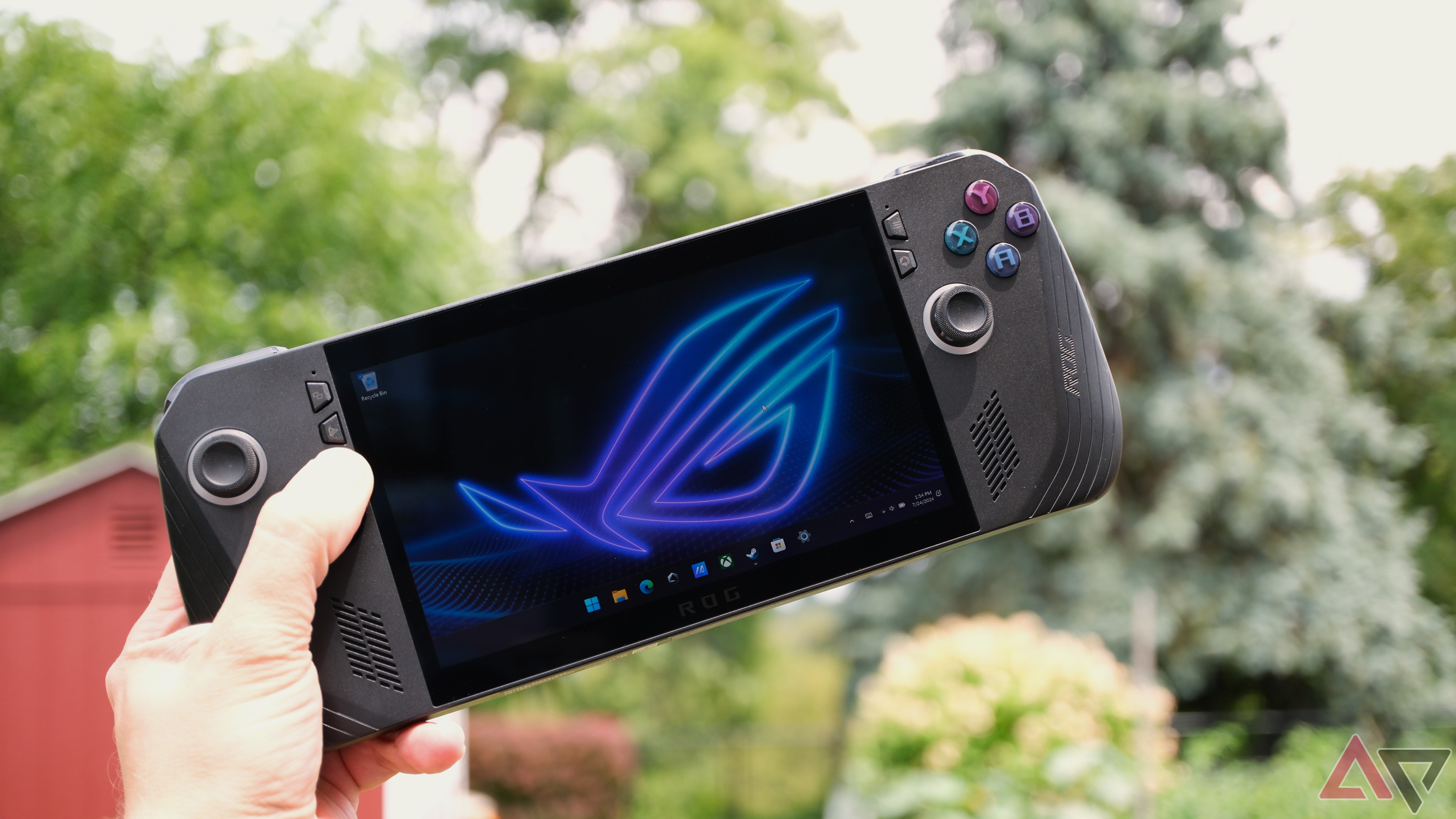 A hand holding an Asus ROG Ally X displaying the home screen